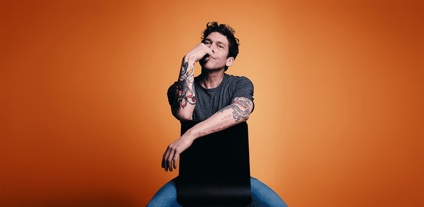 About Me hero section featuring a portrait photograph of Marco Ramos, seated and facing the camera, showing visible arm tattoos. The background is dark gray, with large white text reading 'About me' and navigation links at the top.