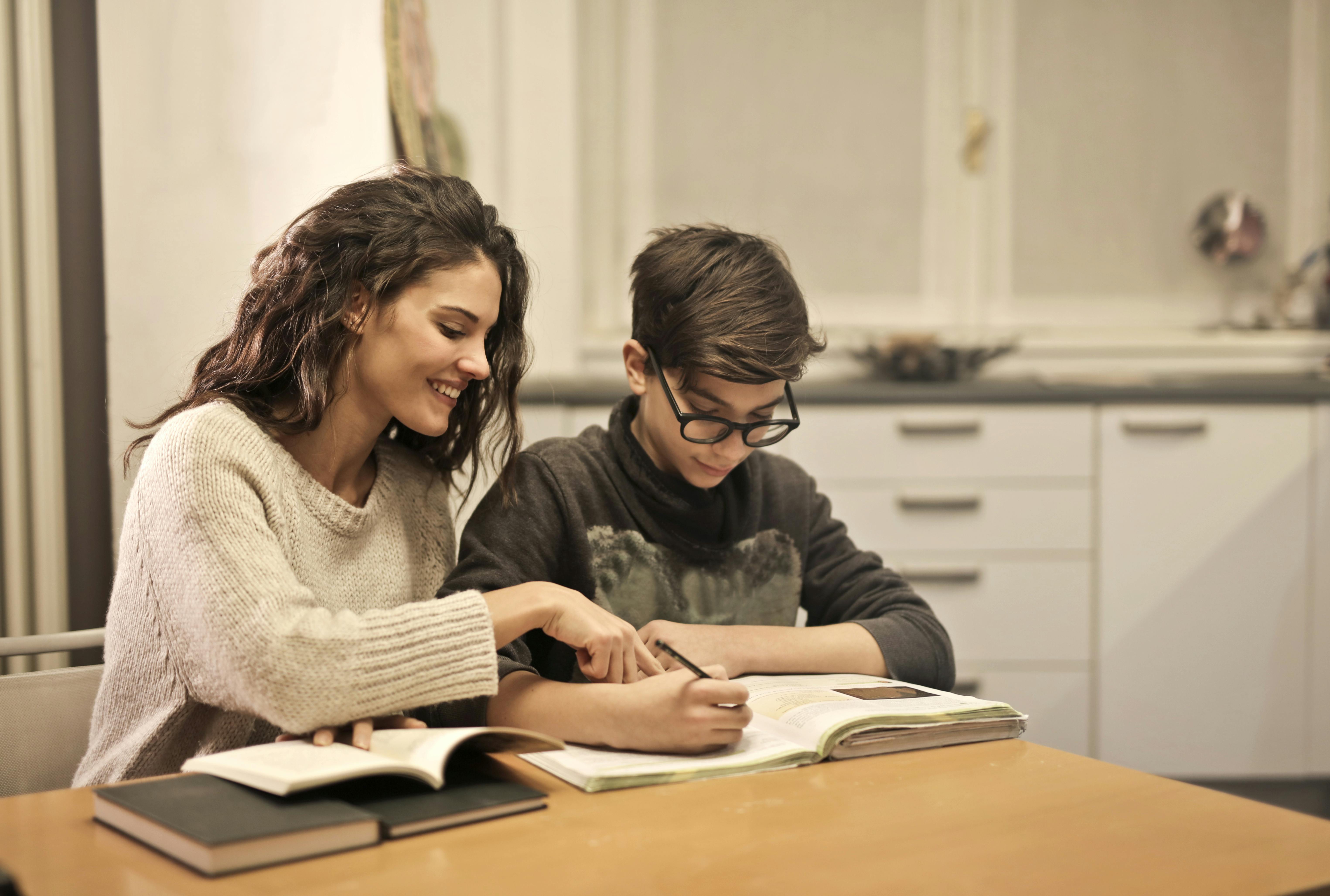 Elder sister and brother studying at home, she's helping him with his homework