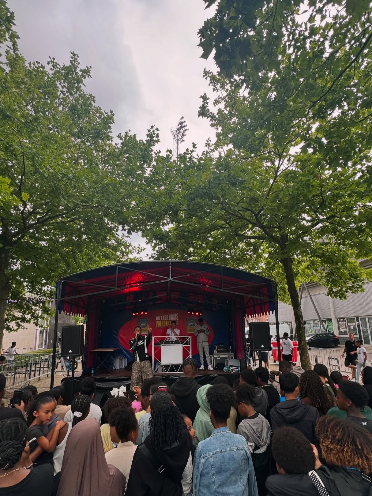Sfeervol evenement met publiek in verlichte zaal met hoge muren en artistieke aankleding.