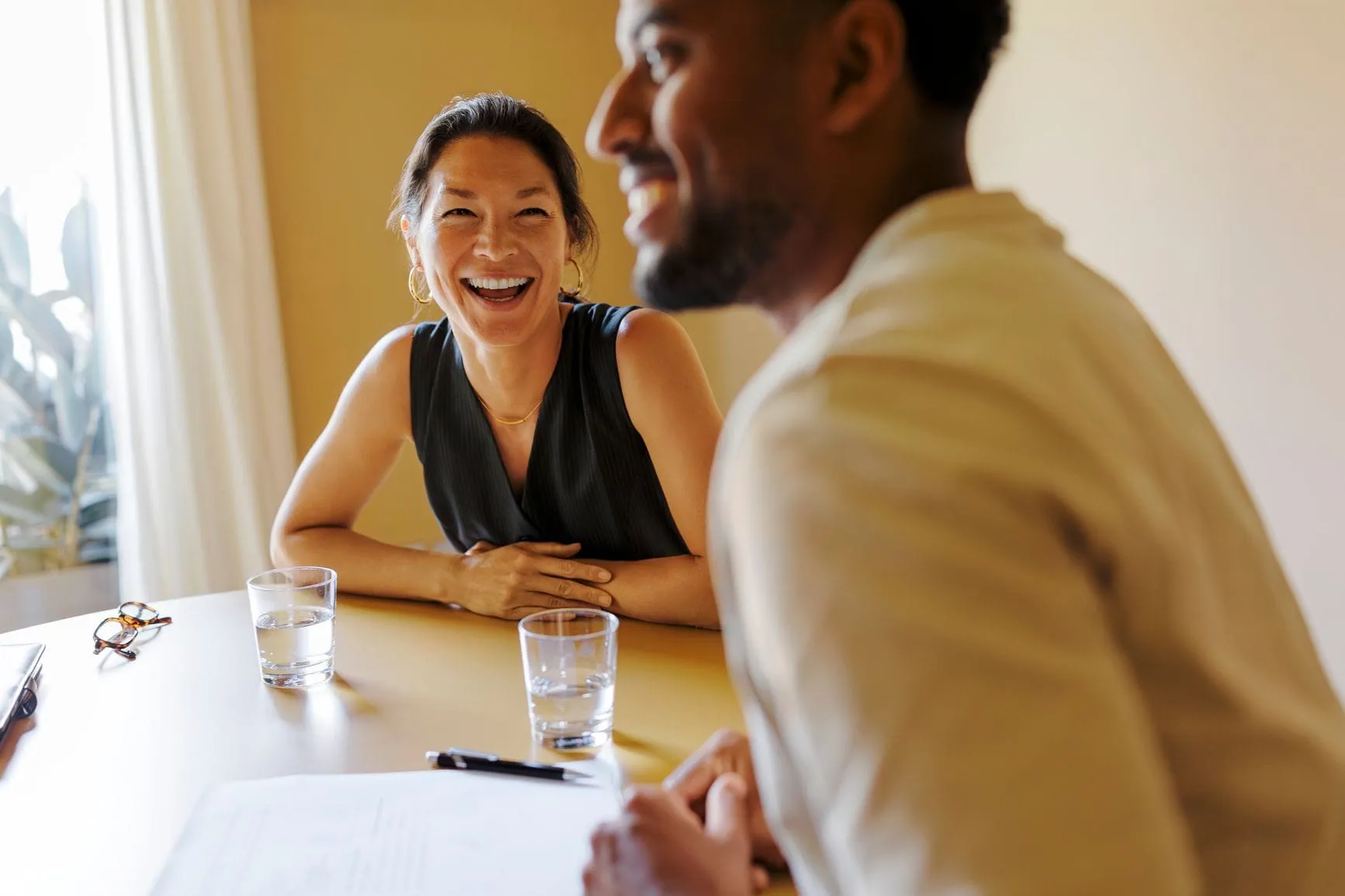 Two clients laughing across the table from their advisor