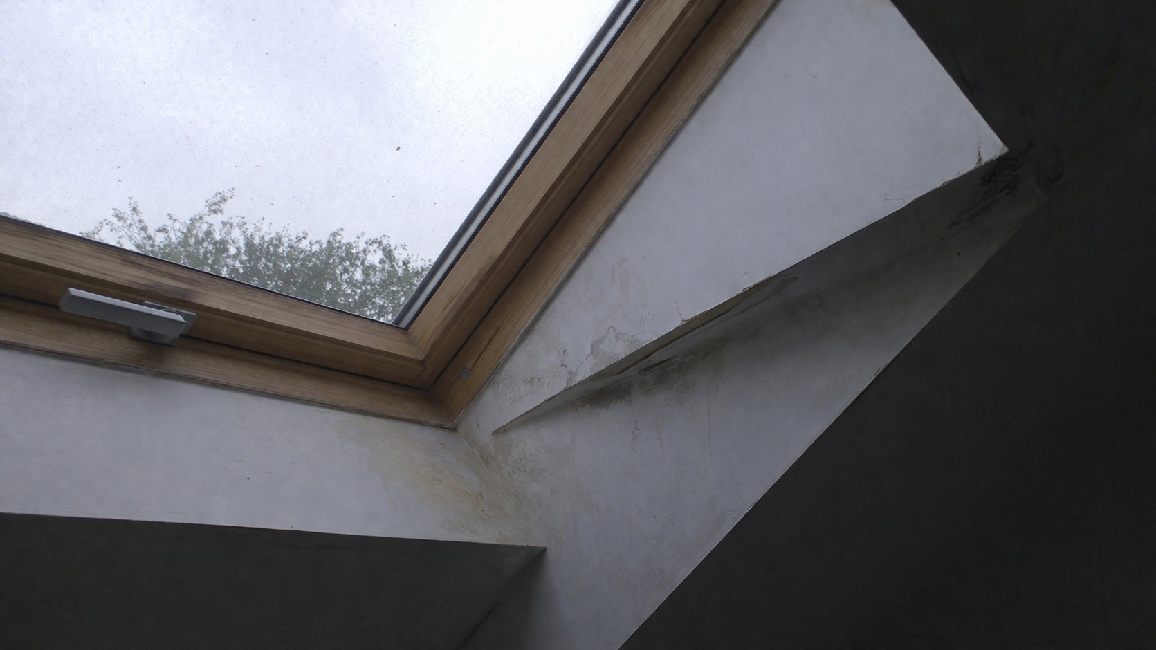 Courant d’air autour d’une fenêtre de toit Velux en pente, avec traces d’humidité sur l’encadrement intérieur des combles