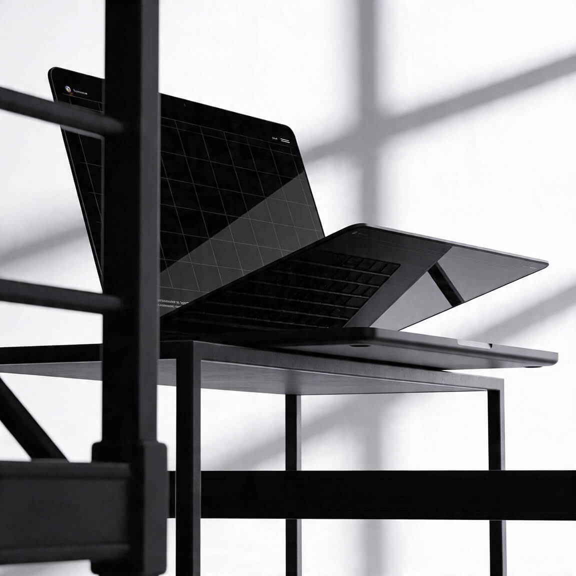 Open laptop mockup placed on a metal structure, with strong shadows creating a high-contrast editorial look.