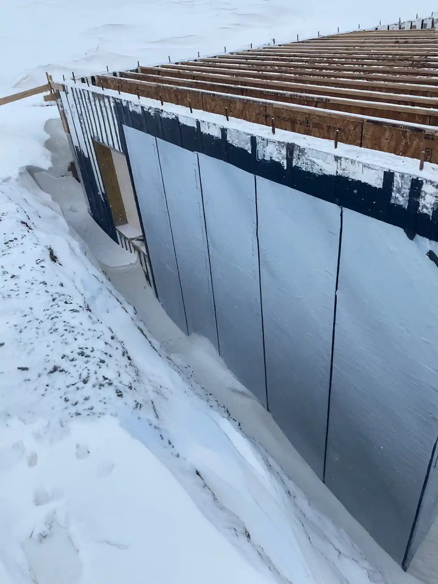 A home being built in winter with peel-and-stick waterproofing the foundation