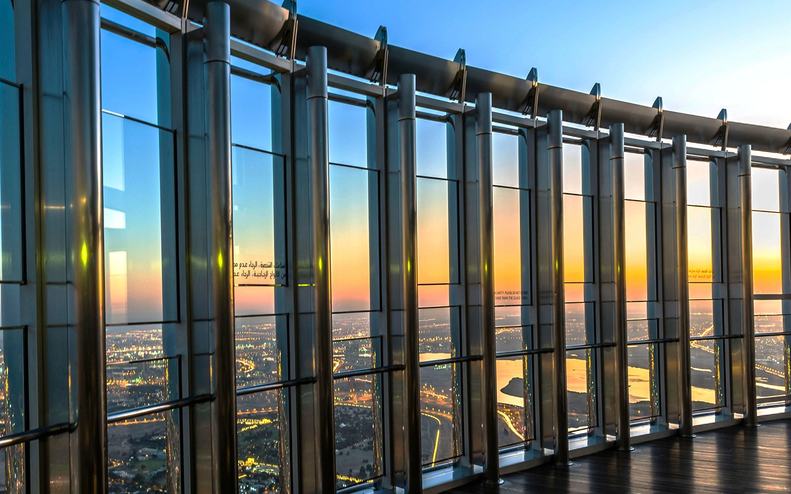 Výhled z úrovně 124 Burj Khalifa při východu slunce, s výhledem na panorámu Dubaje.