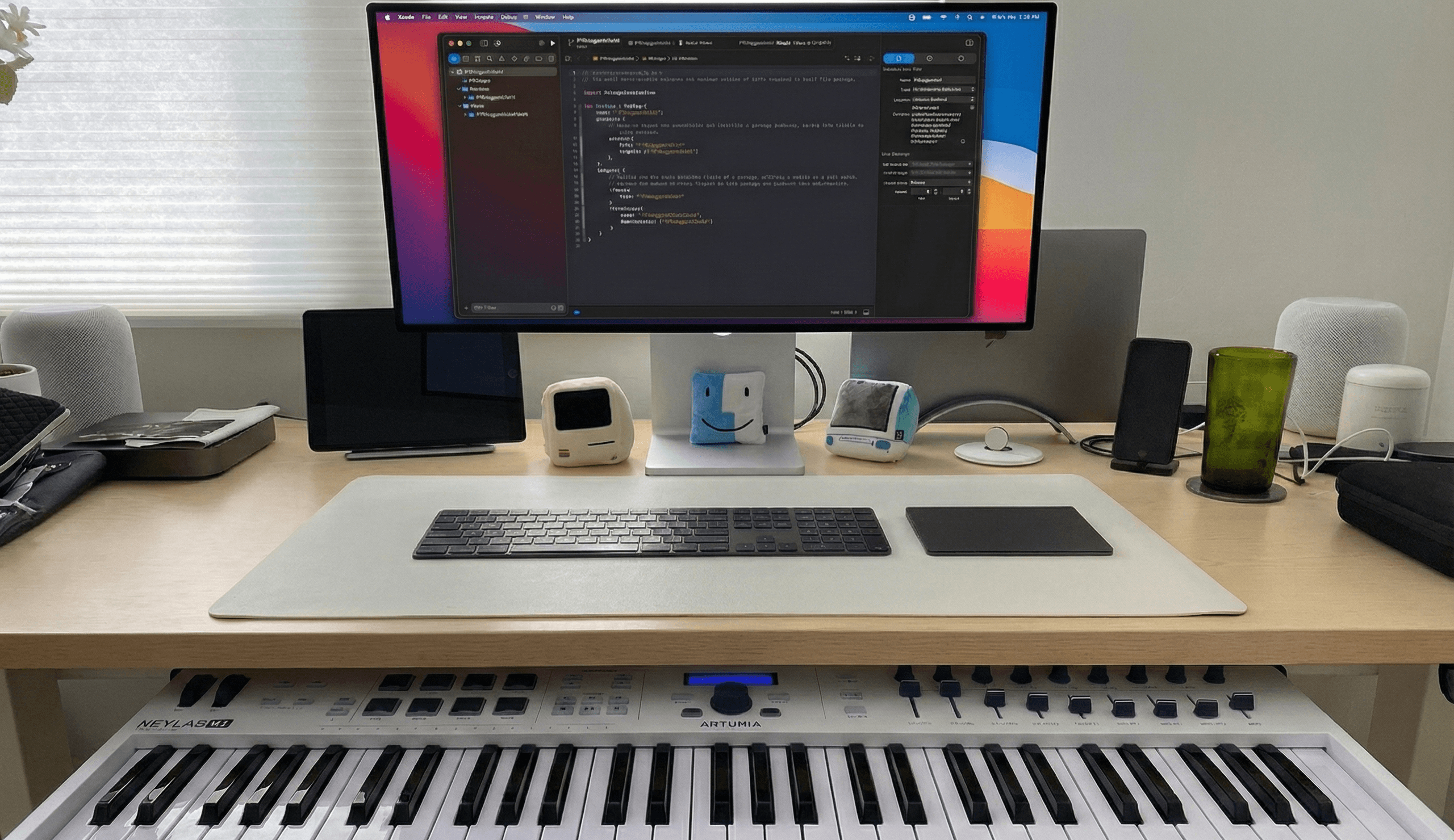 Alex's desk with an Xcode window on the monitor and a piano keyboard sliding out from below the desk