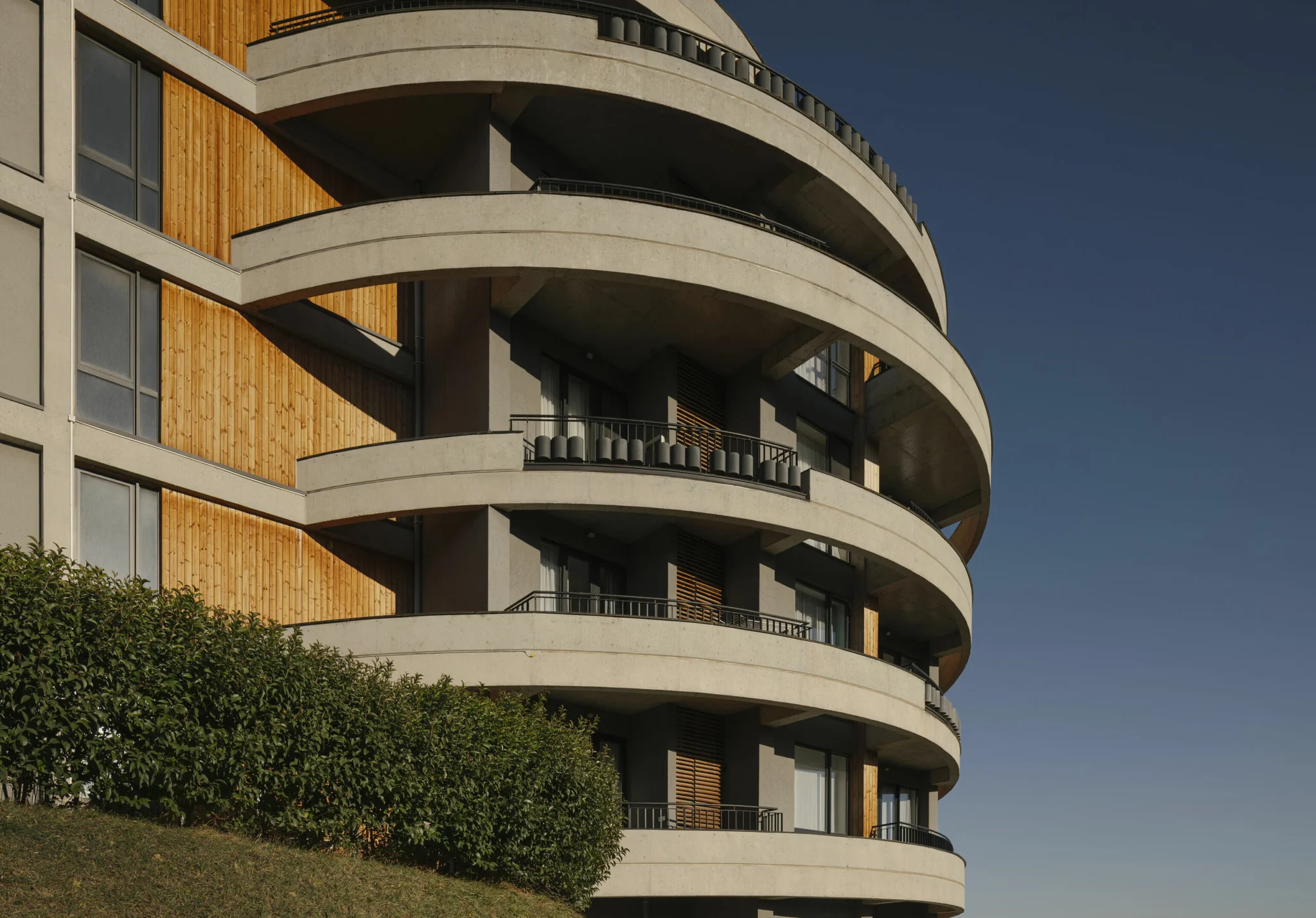 Curved balconies with wooden details and clean concrete lines.