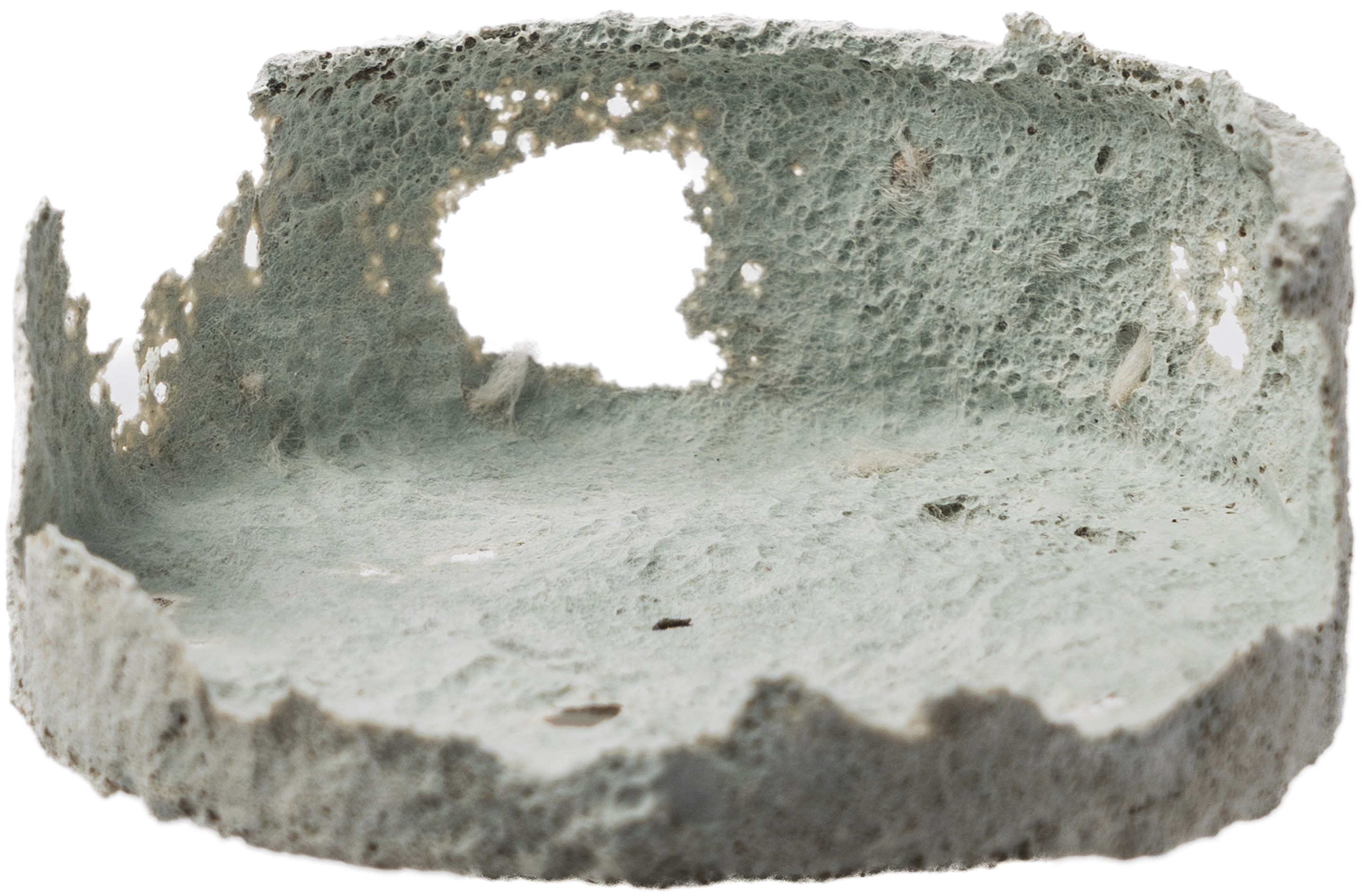 A heavily decomposed 50ml mint-colored Vivomer cosmetic jar sitting in garden dirt, illustrating the rapid home-compostable breakdown of Shellworks' plastic-free sustainable packaging.