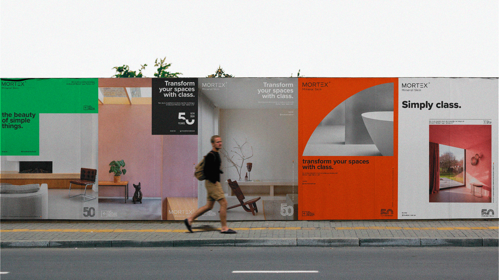 Un mur d’affichage urbain recouvert de grandes affiches Mortex, déclinées en vert, noir, gris, orange et blanc, avec des mises en page franches et graphiques. Un passant traverse la scène, apportant une dimension réaliste et renforçant l’esthétique urbaine, architecturale et publicitaire de l’ensemble.