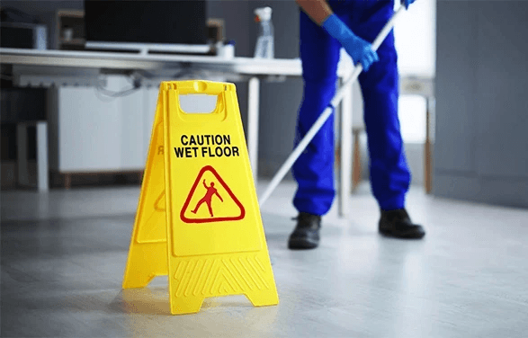 Floor being mopped with a visible wet floor sign, symbolizing preventable slip-and-fall hazards on commercial property