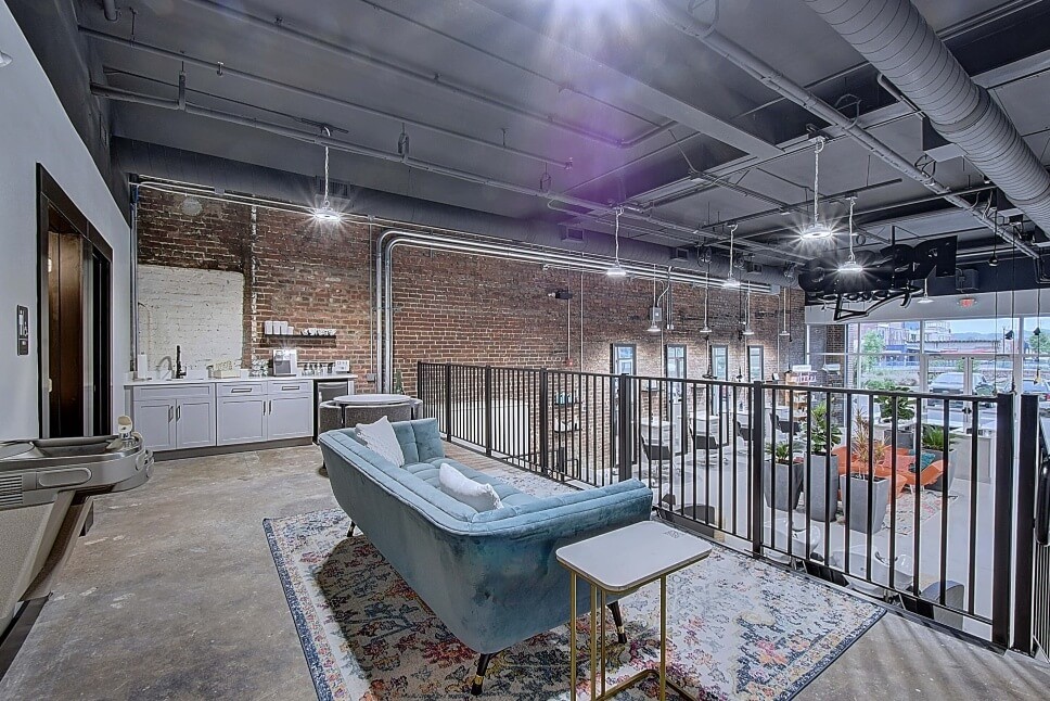 A modern interior space showcasing a sleek design with a couch, end tables, and large windows.