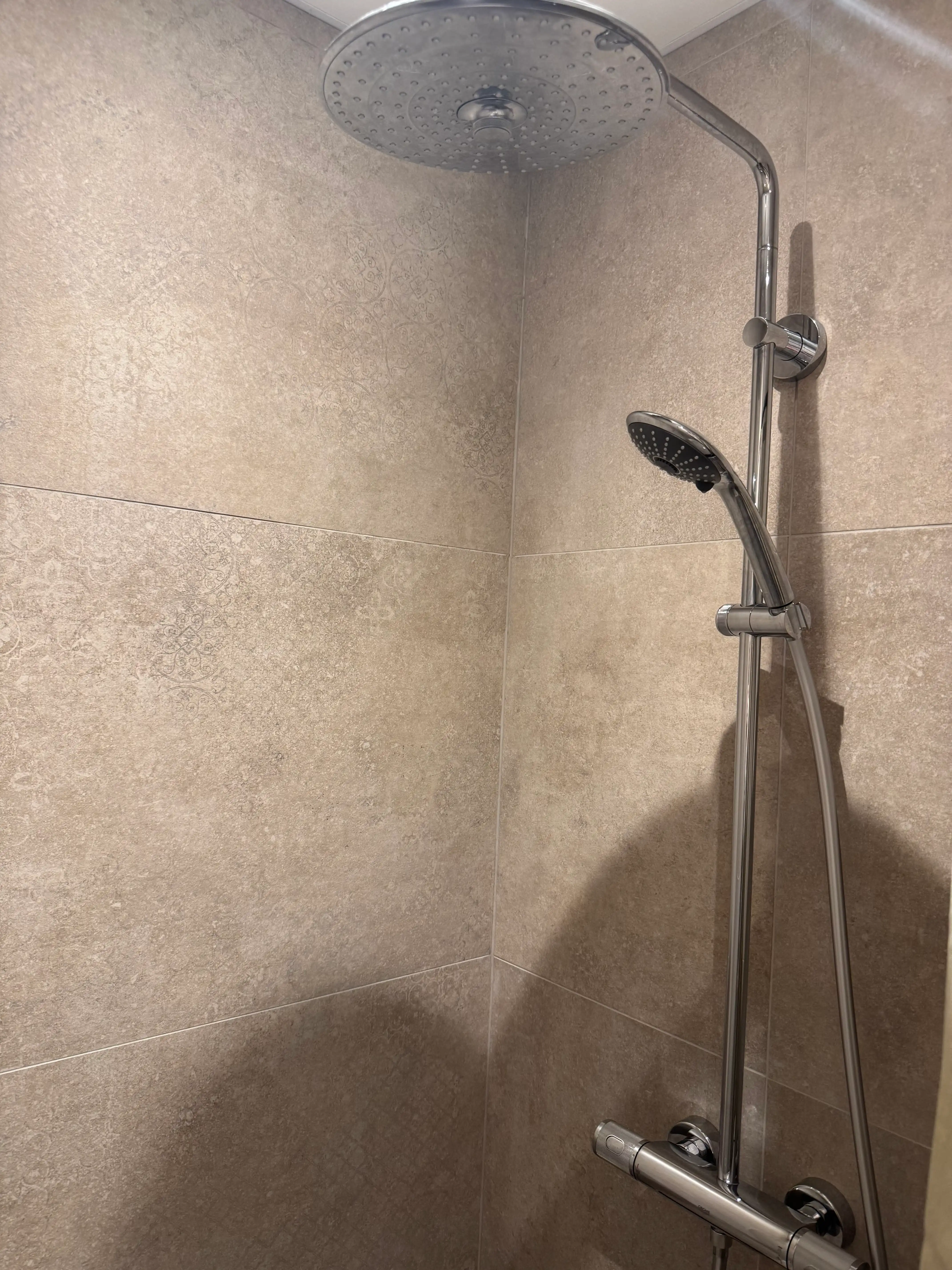 Luxe regendouche met beige tegels in modern appartement.