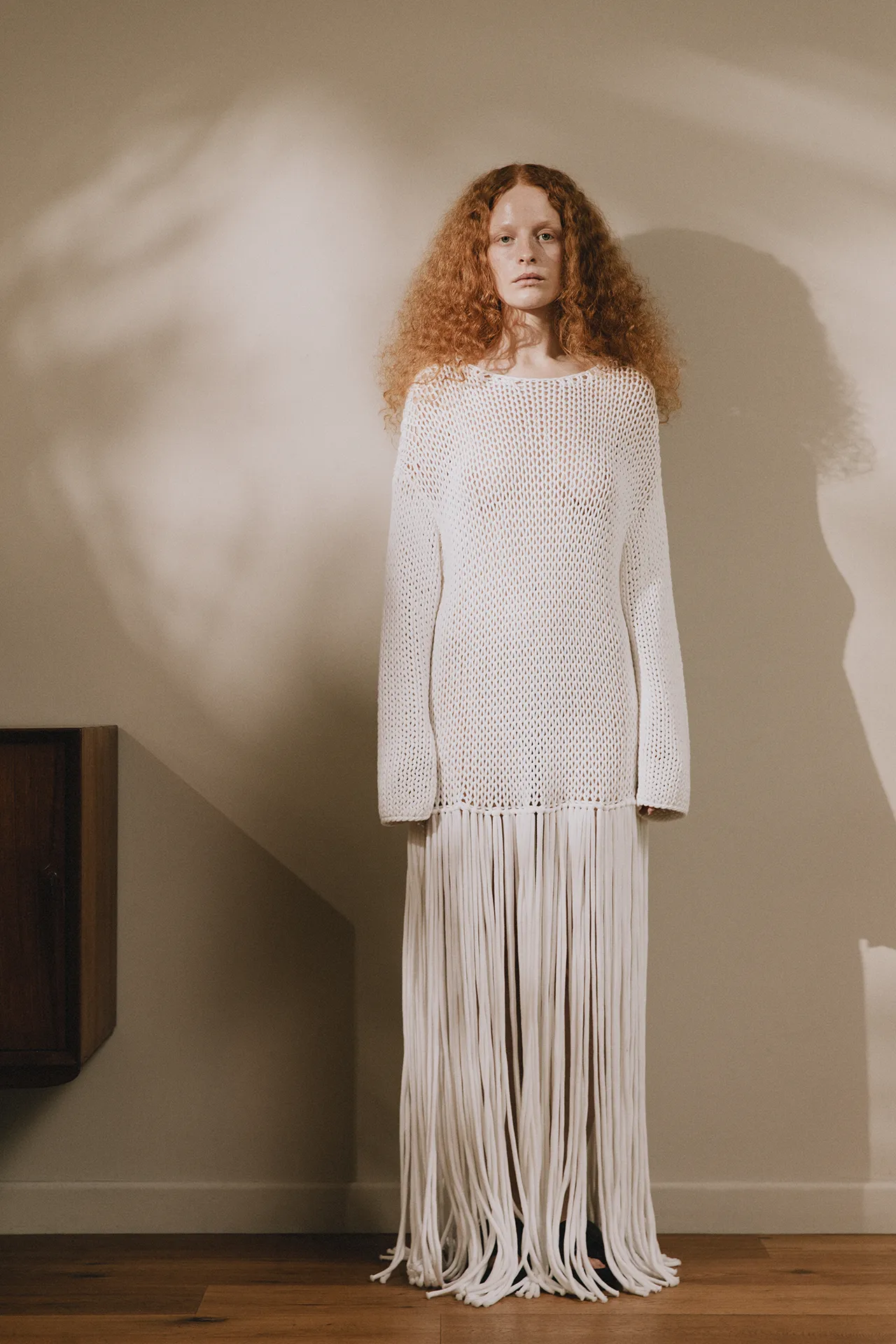 Full-length view of Annapurna SS26 collection white crochet-style knit dress with floor-length fringes.