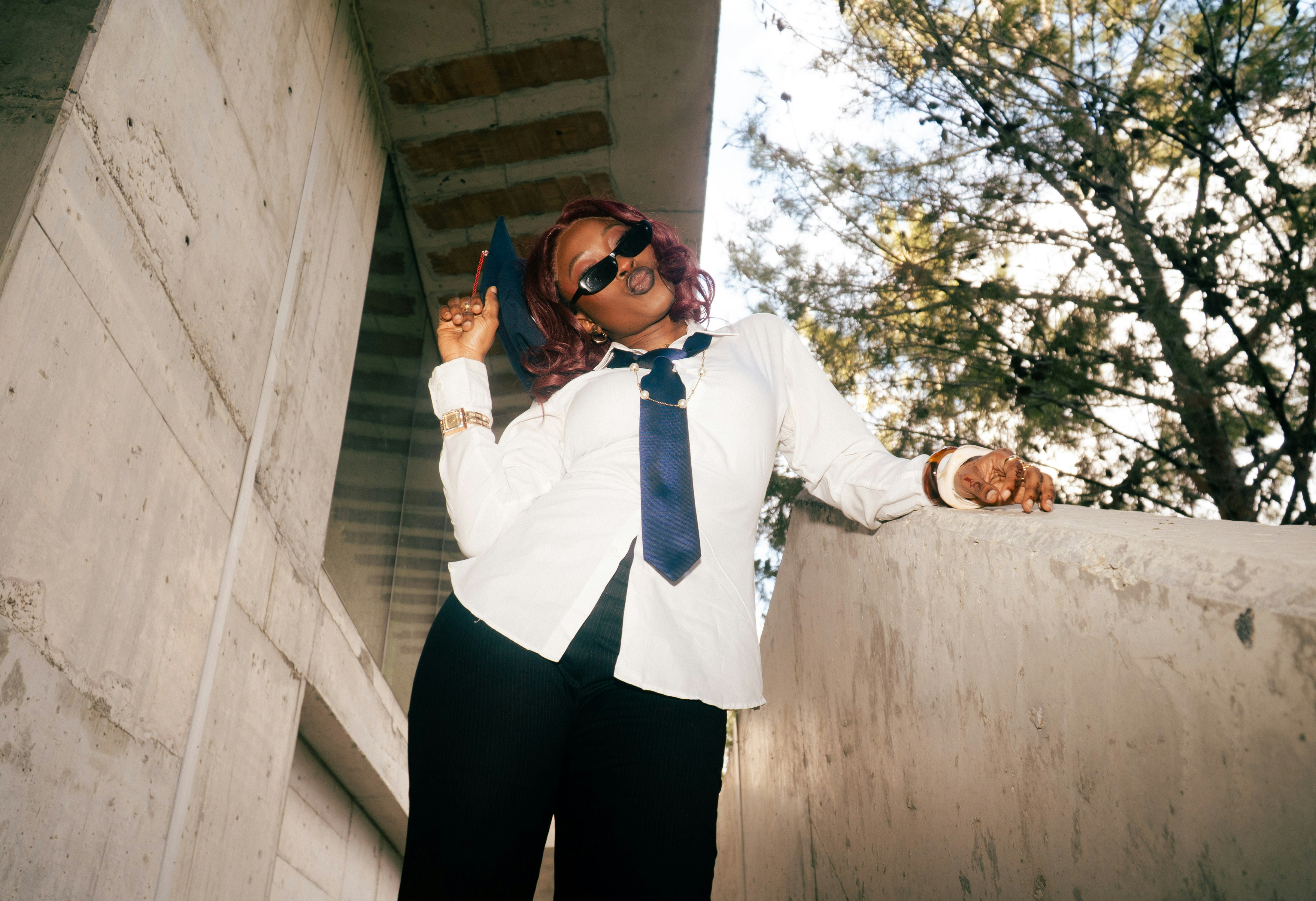 Woman in white shirt and tie poses outdoors