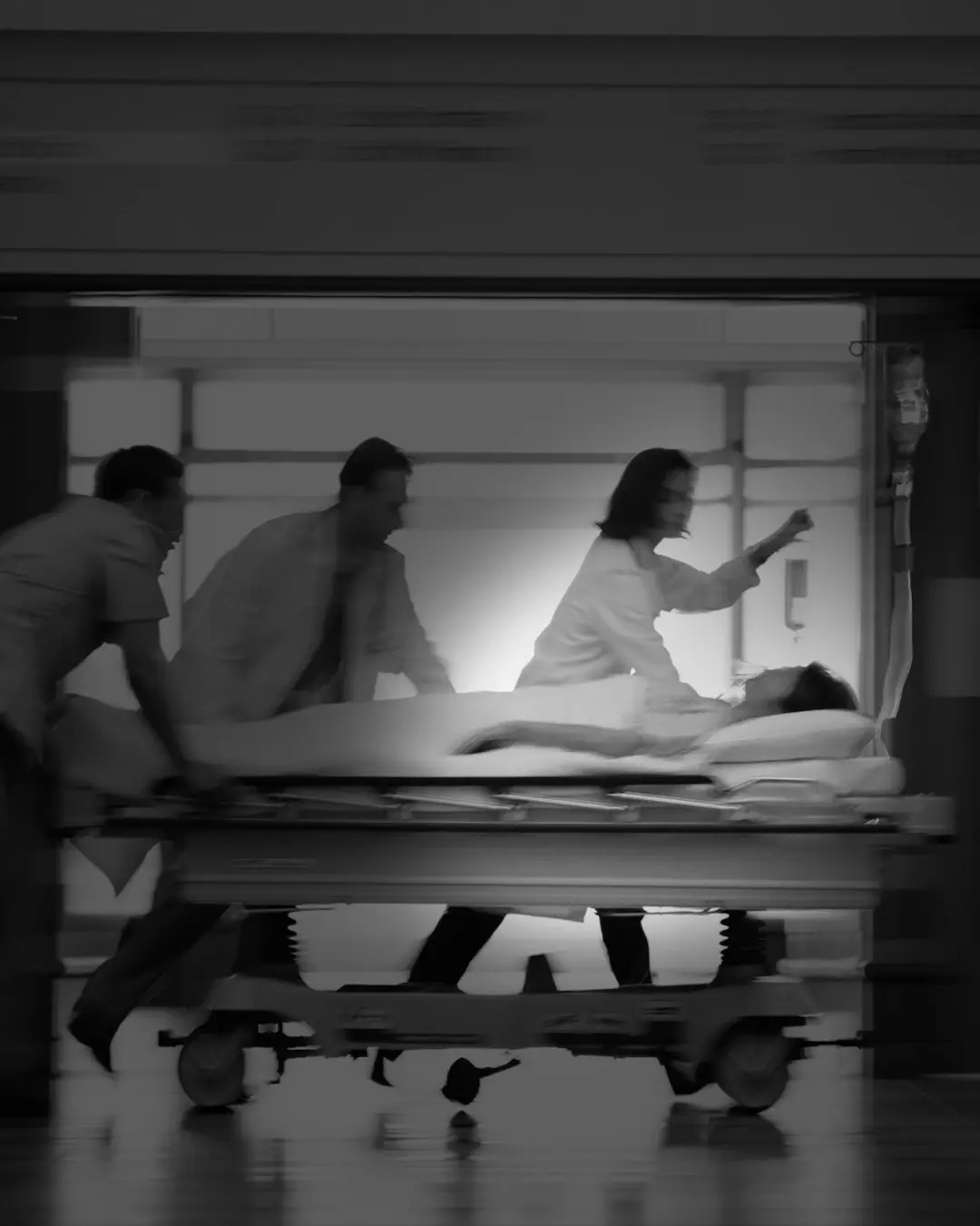 A team of medical professionals urgently wheels a patient on a stretcher through a hospital corridor, highlighting emergency response and hospital care.