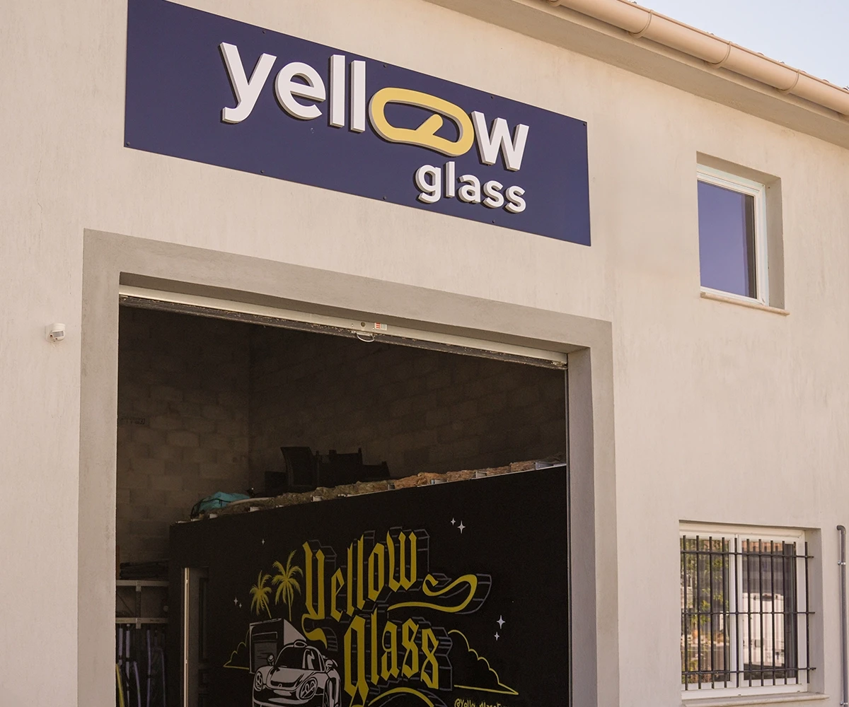 Enseigne "yellow glass" sur un bâtiment blanc avec une porte ouverte, affichant le logo de l'entreprise.