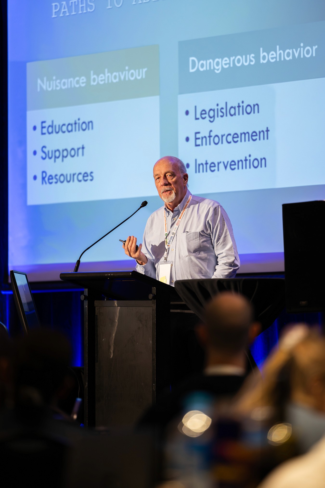 Man speaking on stage in front of presentation at conference