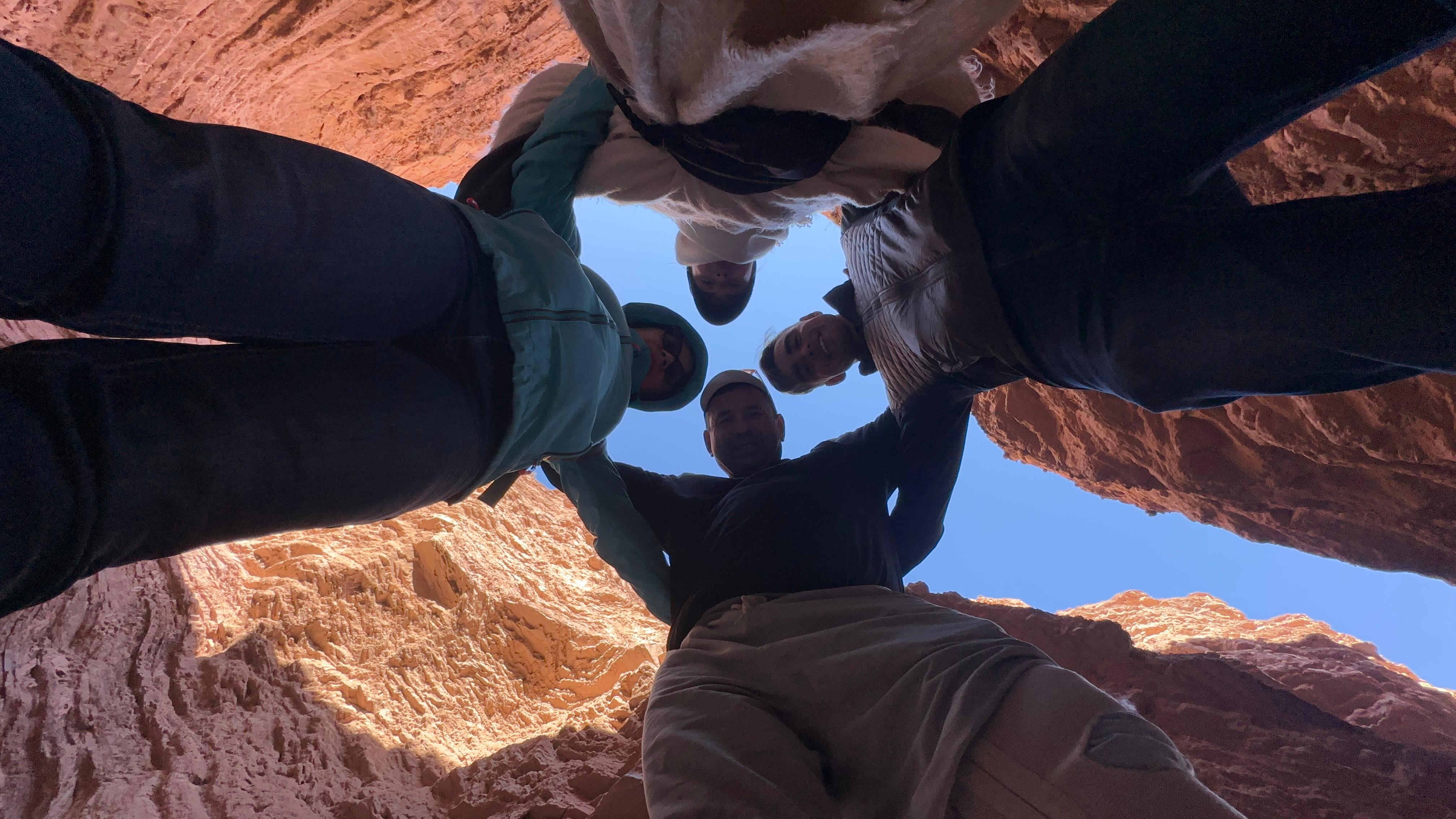 Mujer sentada sobre un tronco frente a una cascada doble en un bosque frondoso de Argentina.