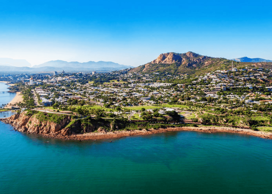 Coastal city viewed from above with a prominent mountain in the background.