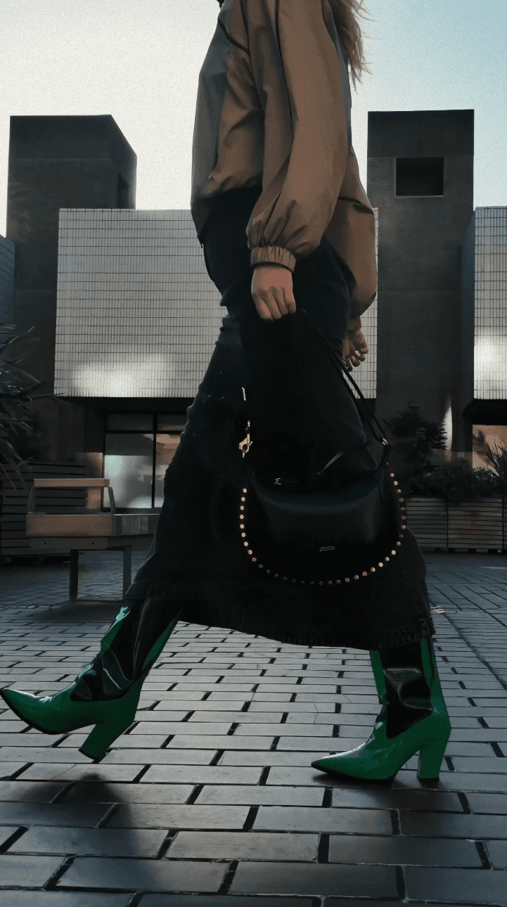 Person's hand petting Shiba Inu dog among fallen leaves