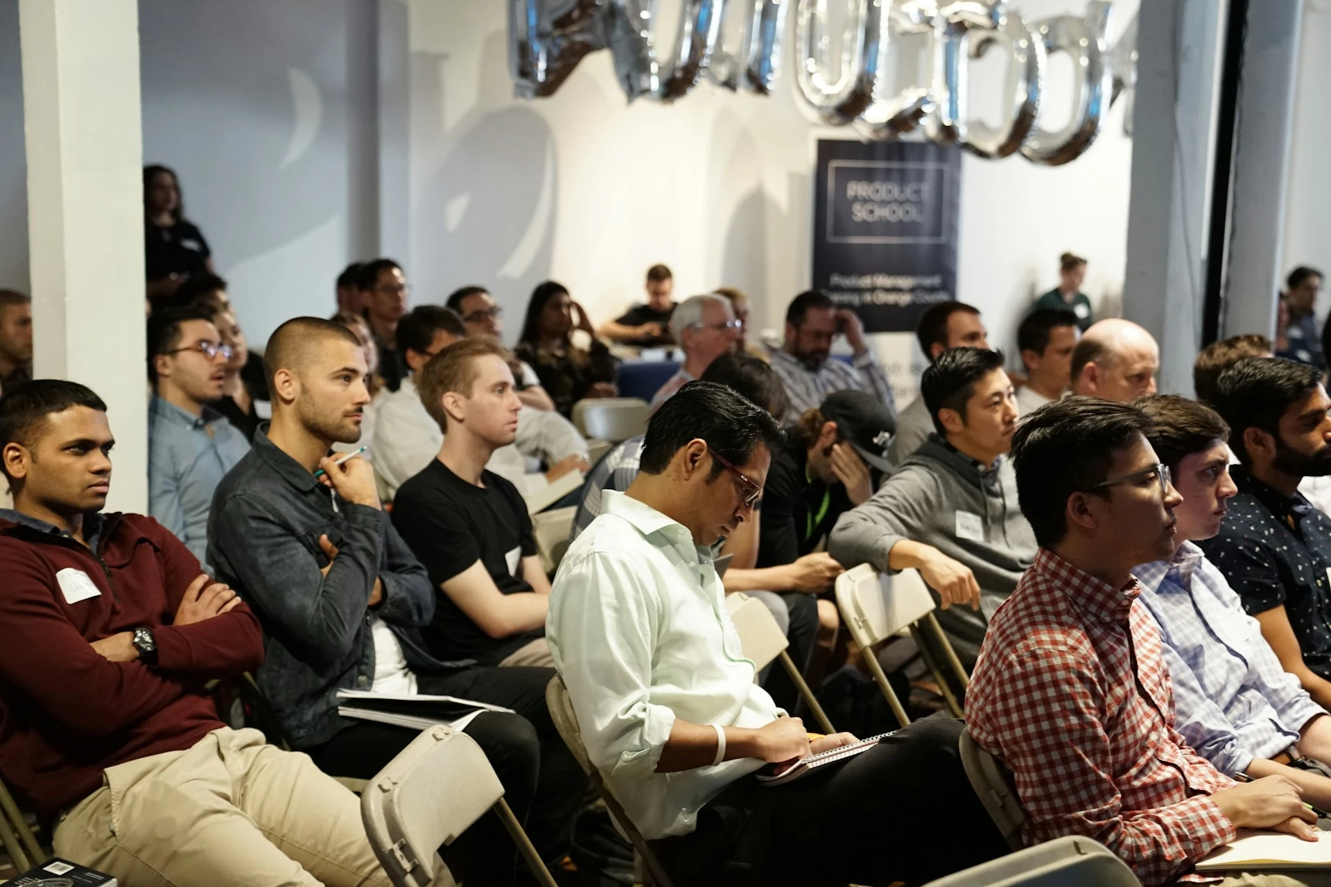 High school students at a summer program or RISE Research event on product management; audience listens to speaker at professional workshop on design and training.