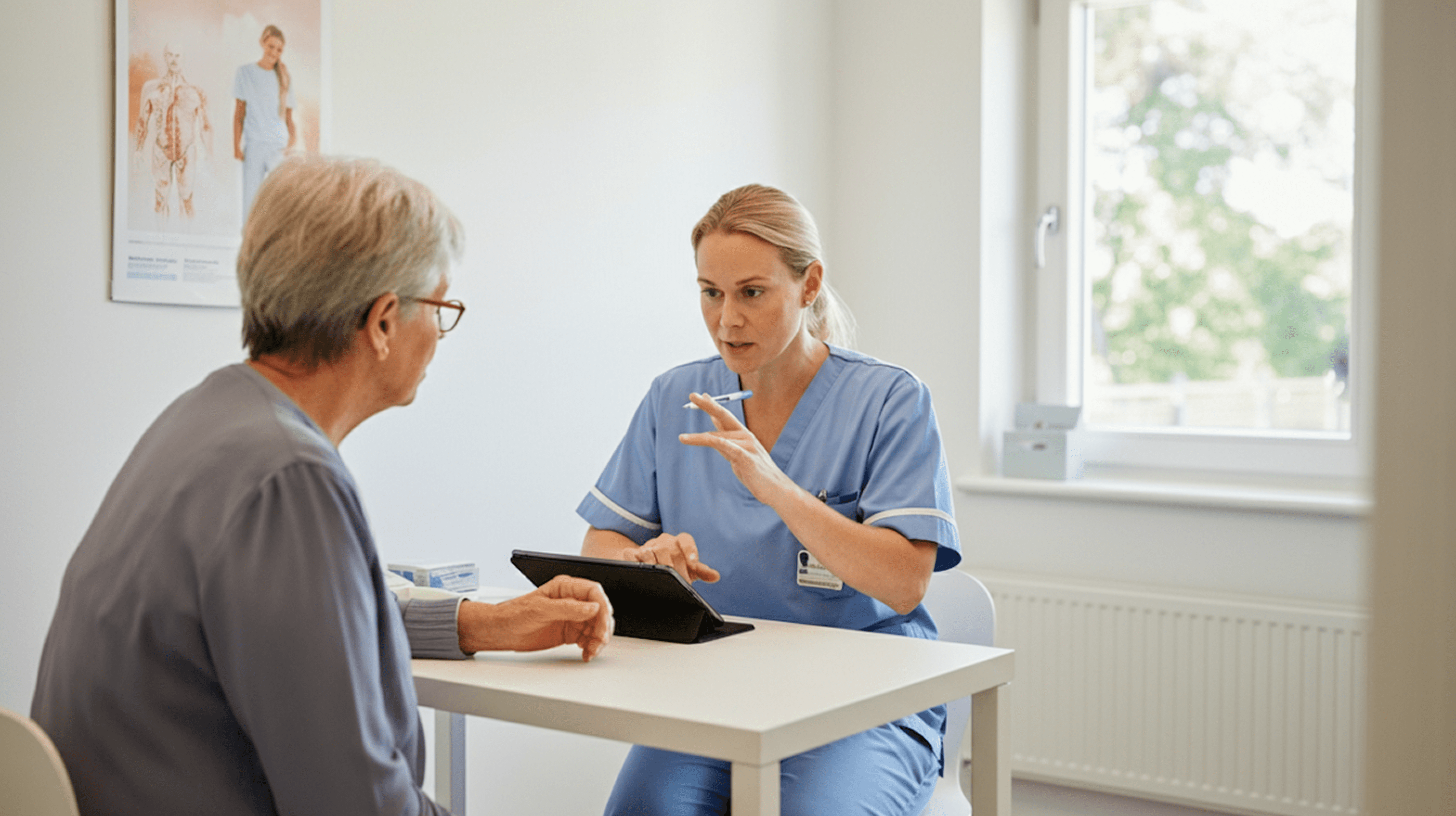 Healthcare professional in blue scrubs discussing treatment with older patient using tablet in medical office