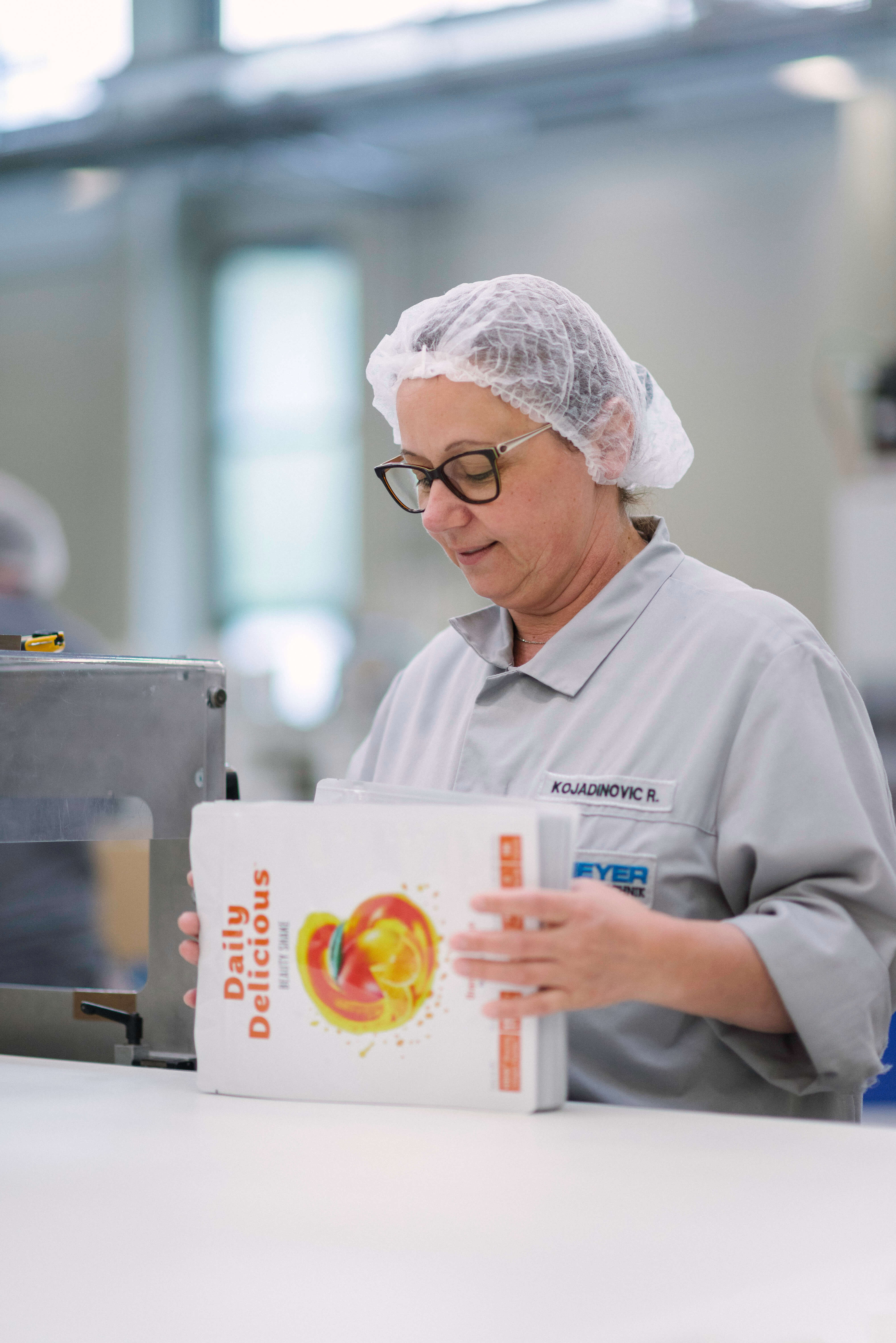 Scheyer employee carefully stacking finished packaging products, ensuring alignment and order in the production line.