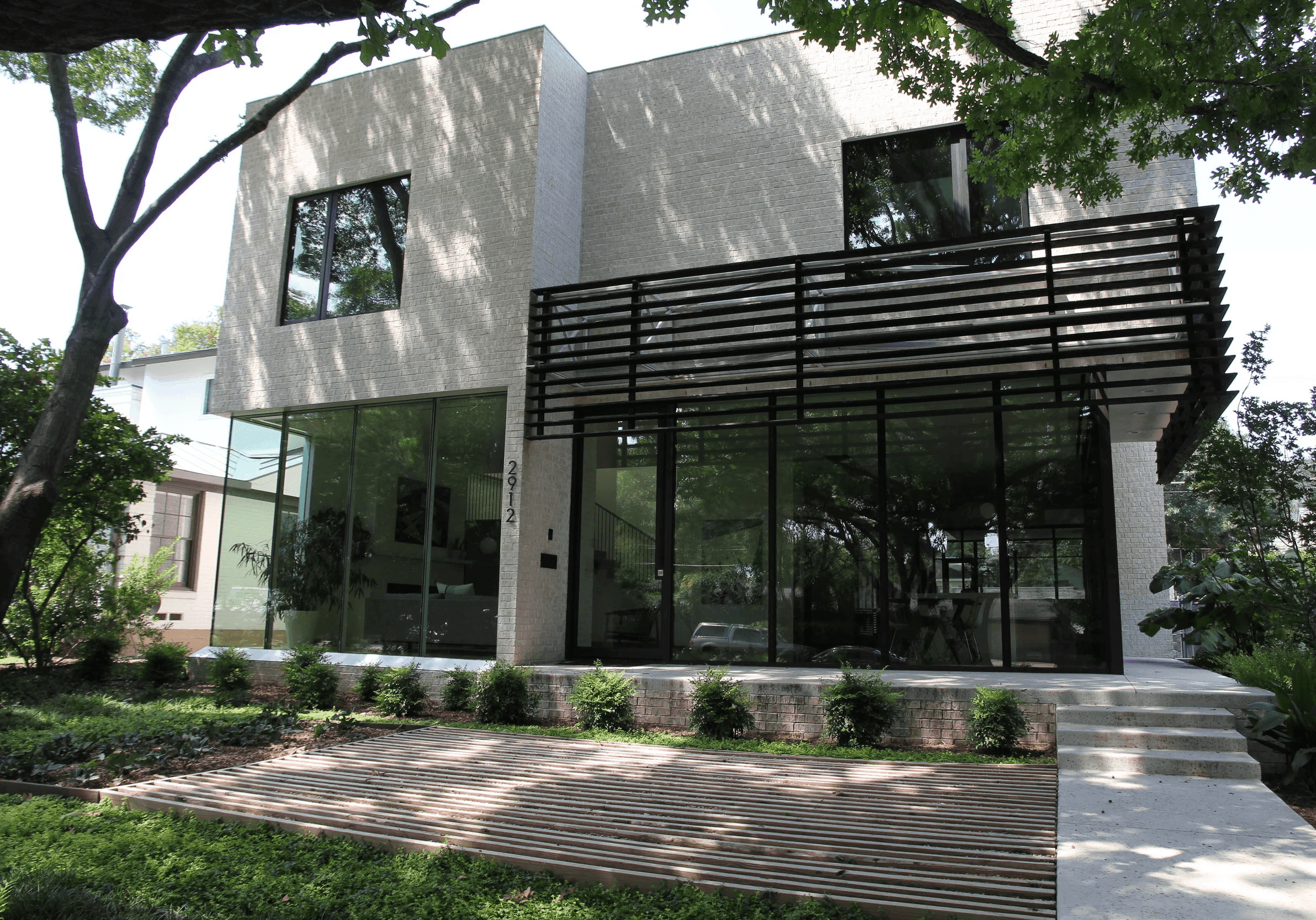 White modern home with a dark slatted privacy screen above the glazed lower level