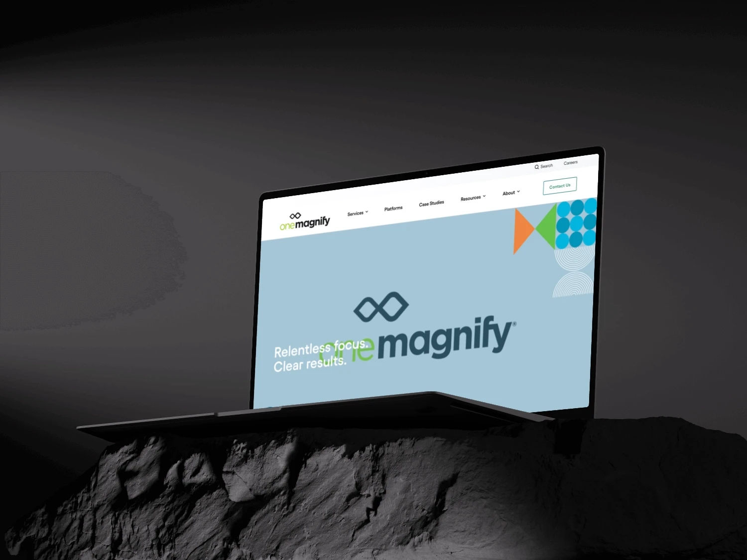 One Magnific Website displayed on a macbook standing on a black rock