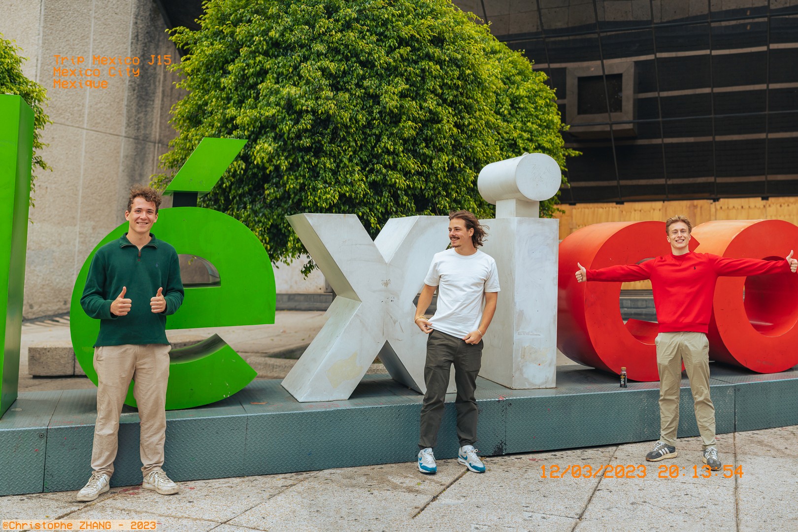 Groupe d'amis prenant la pose devant l'enseigne emblématique "México" à Mexico City.