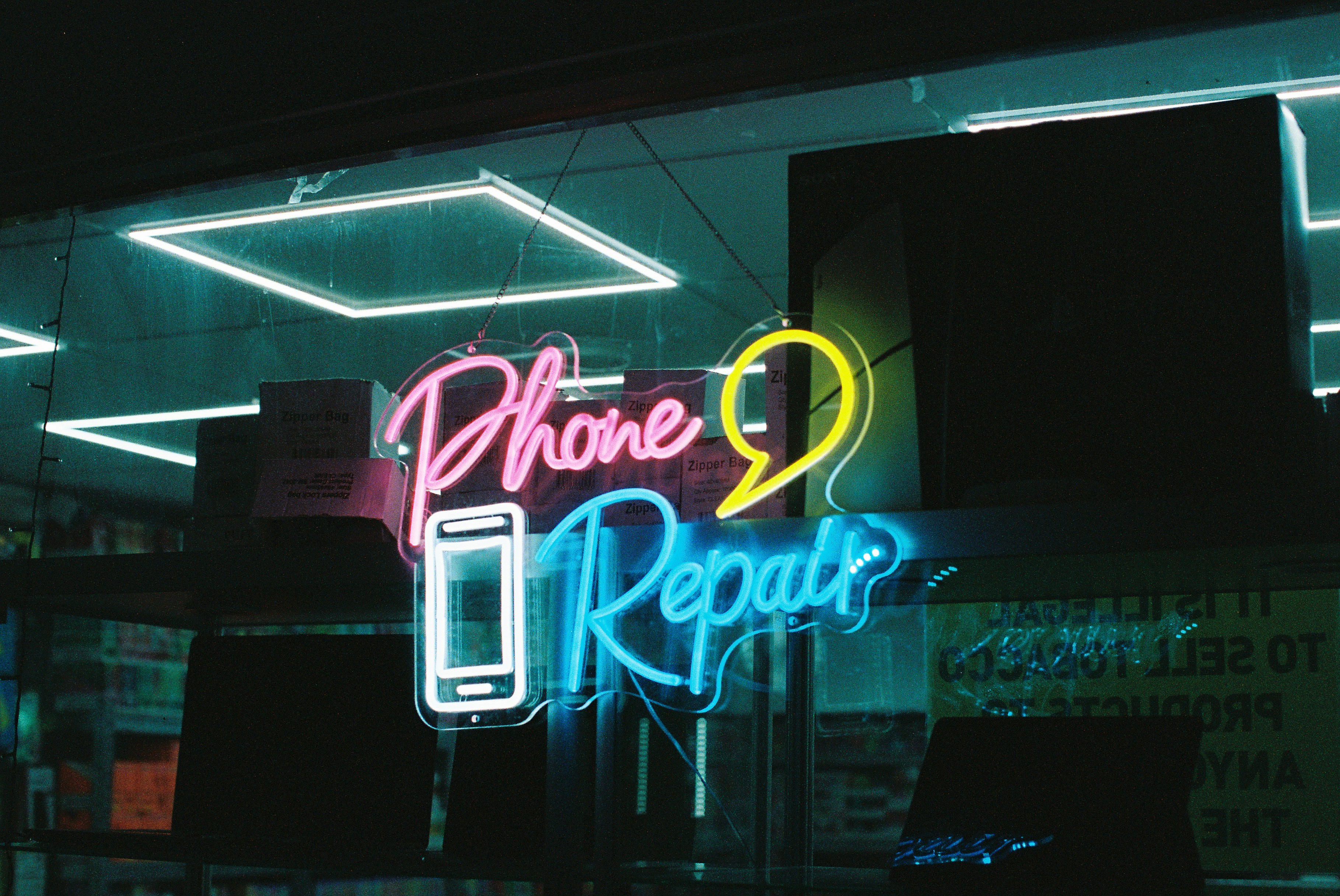 Neon "phone repair" sign with smartphone icon of a smartphone.