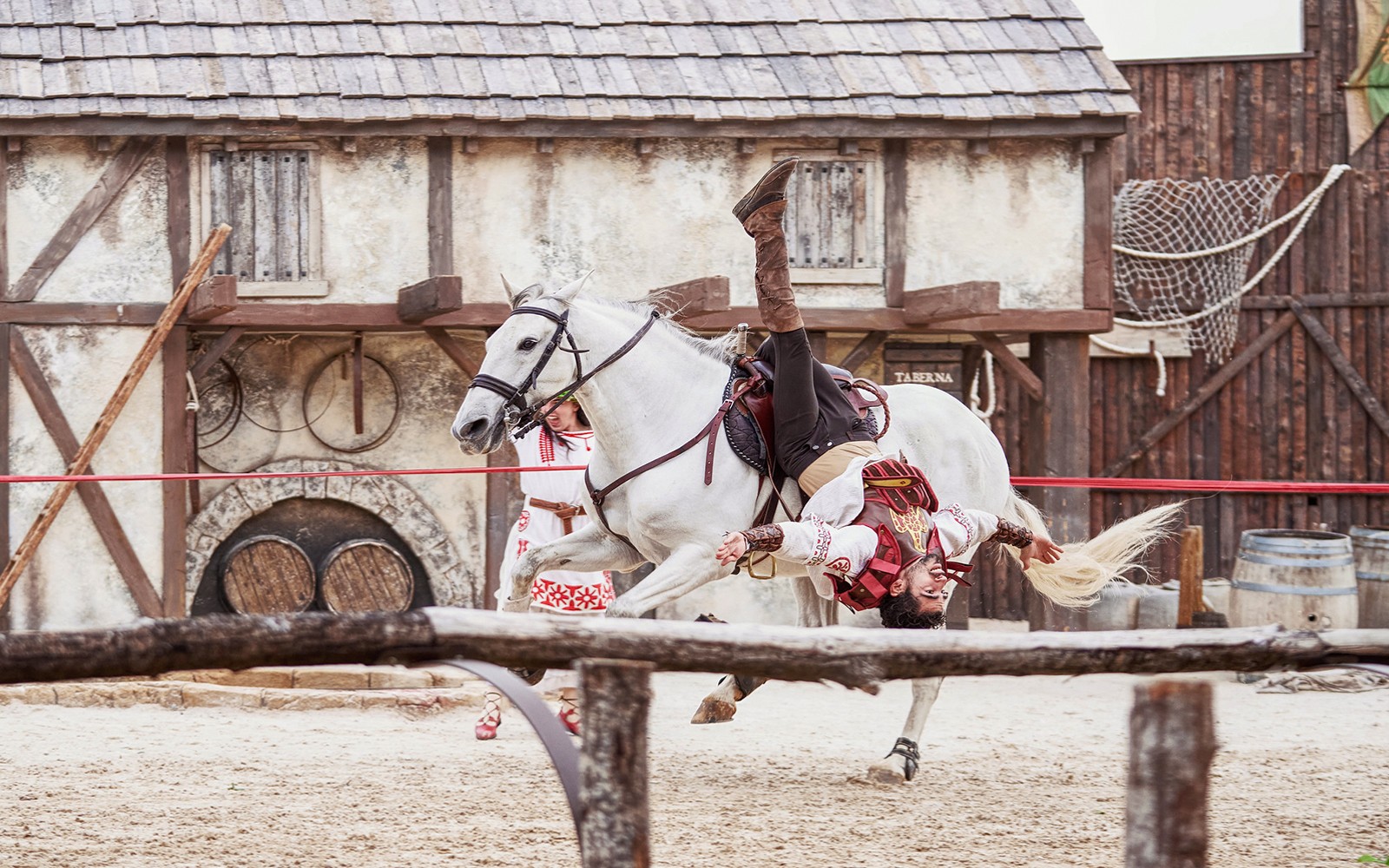 Performer in costume doing acrobatics on a white horse at Puy du Fou España.