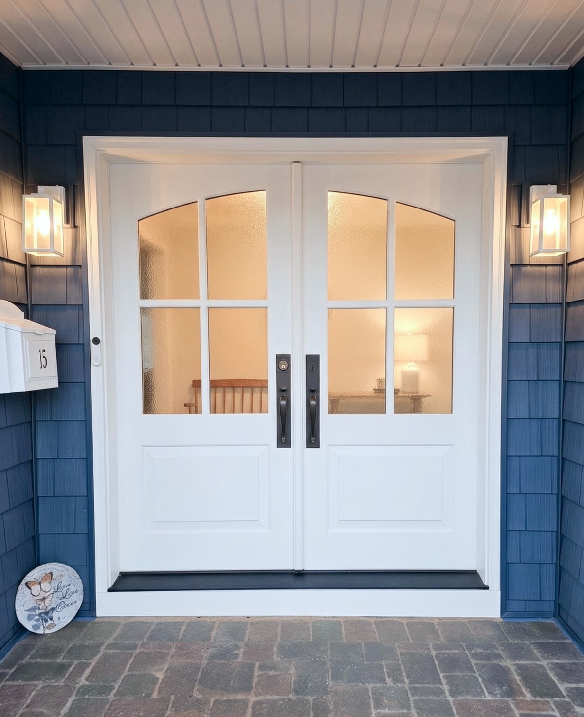 Exterior renovation with custom front entry doors, blue siding, and modern outdoor lighting fixtures