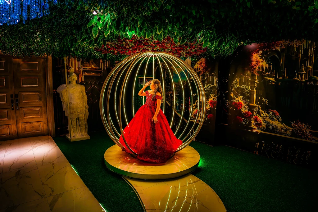Debutante in a red ballgown inside the golden sphere at Pandora Hall