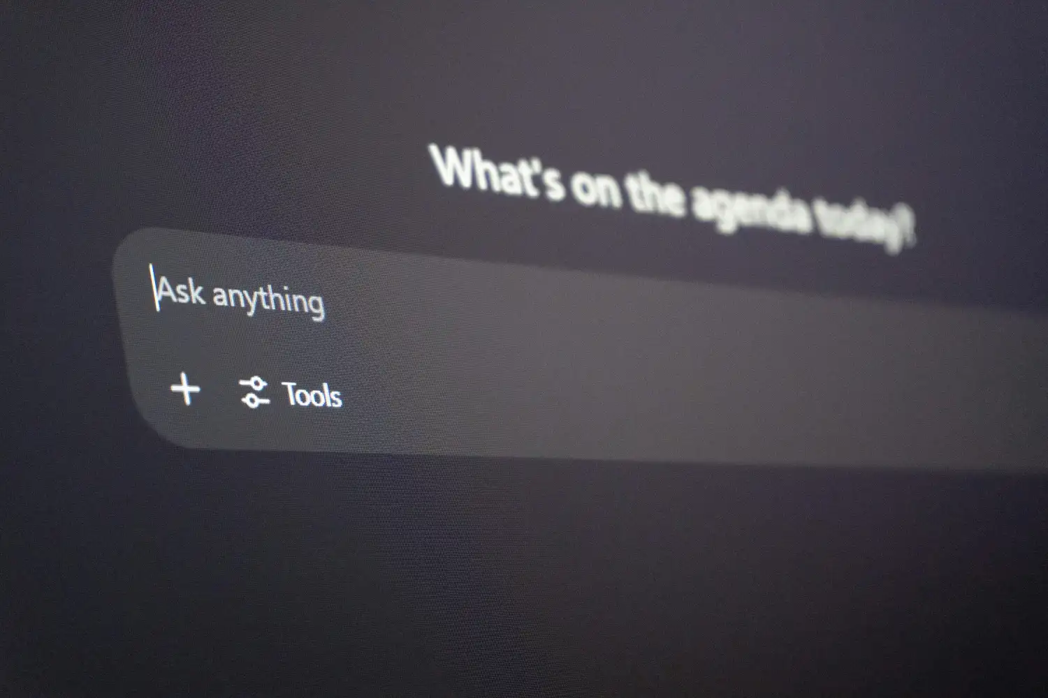 Close-up of a computer interface with "Ask anything," "What's on the agenda today?" and icons for tools.