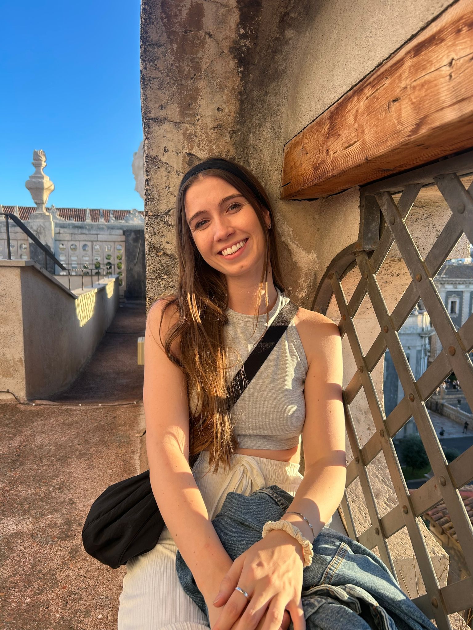 Traveler sitting on desert rocks during the Desert Sky tour in AlUla, smiling and holding binoculars.