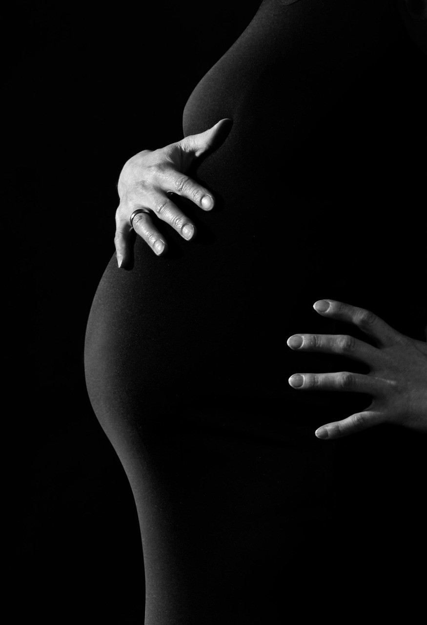 Une photo en noir et blanc d'une femme enceinte, montrant son ventre en silhouette.