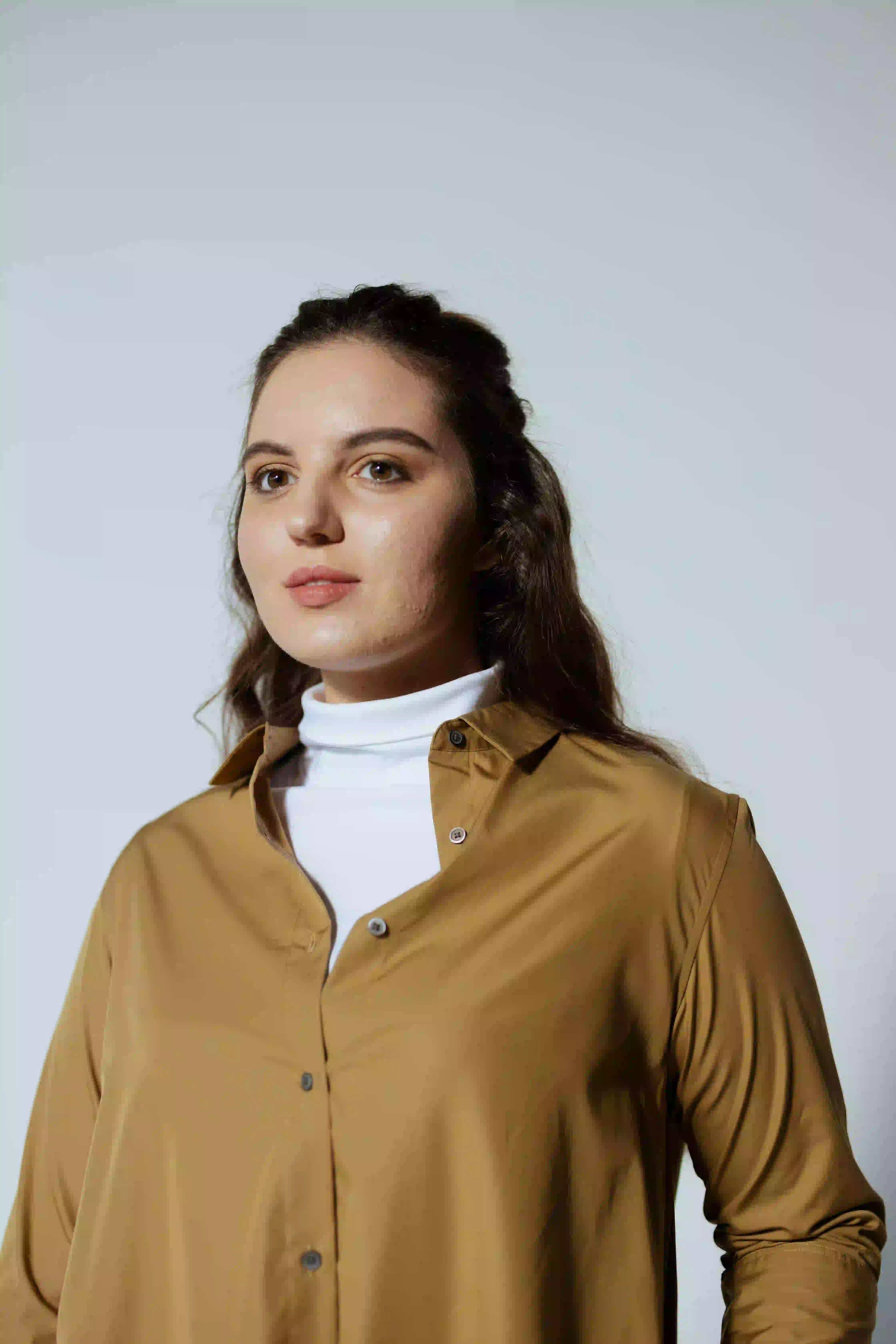 woman looking sideways leaning on white wall