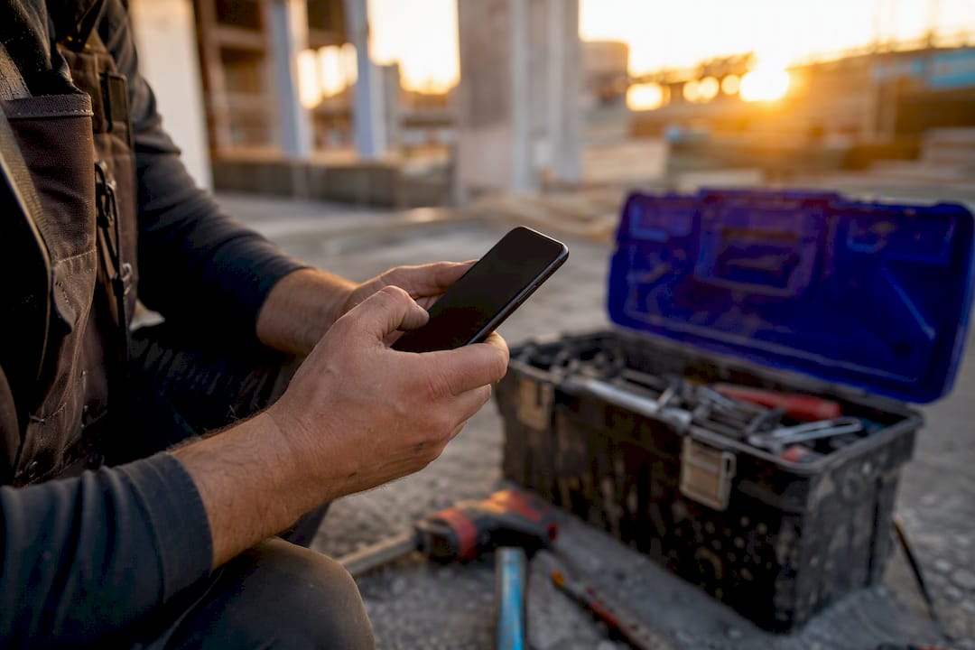 Contractor texting on smartphone outdoors