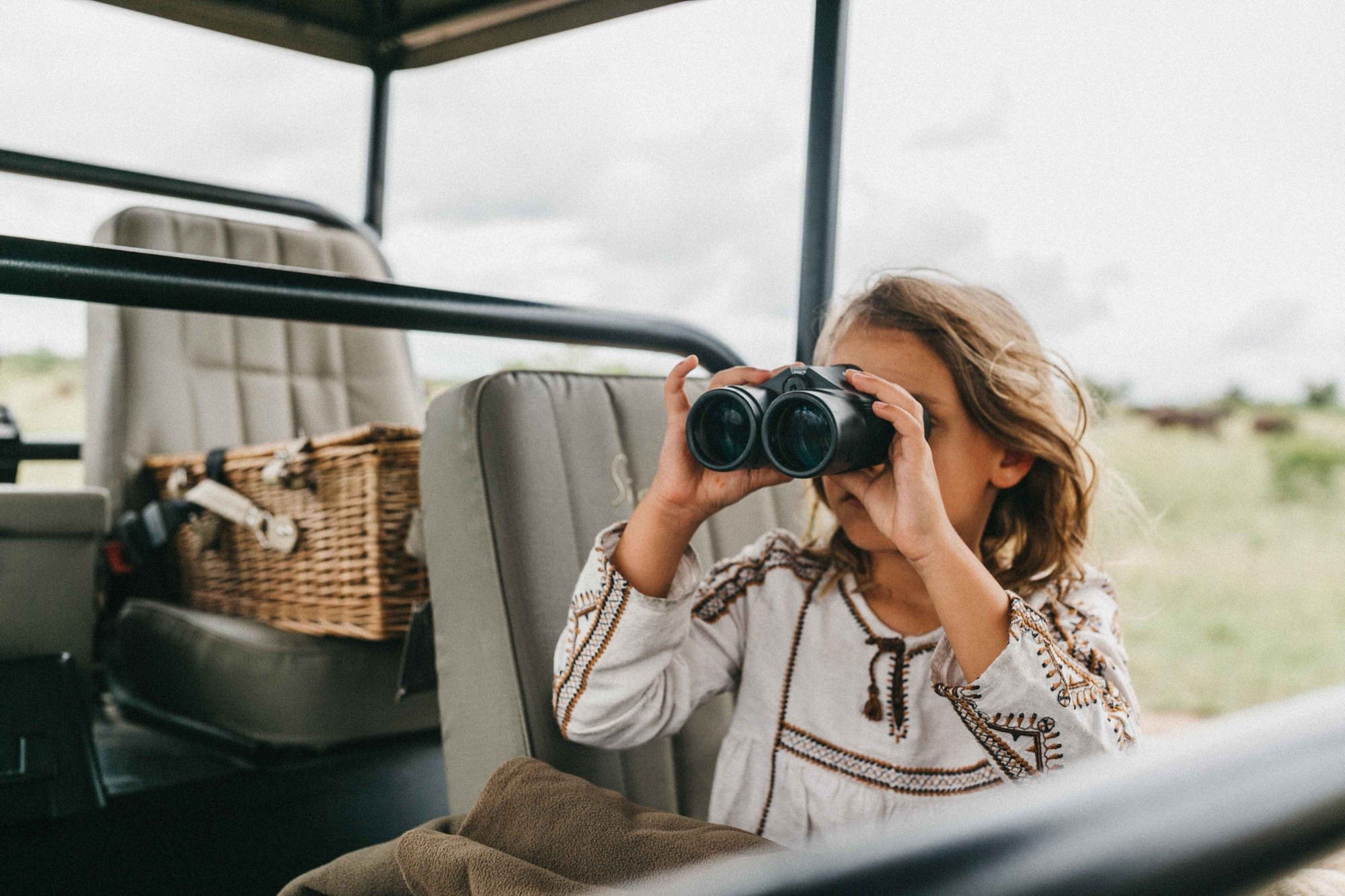 A young girl scanning the plains through binoculars
