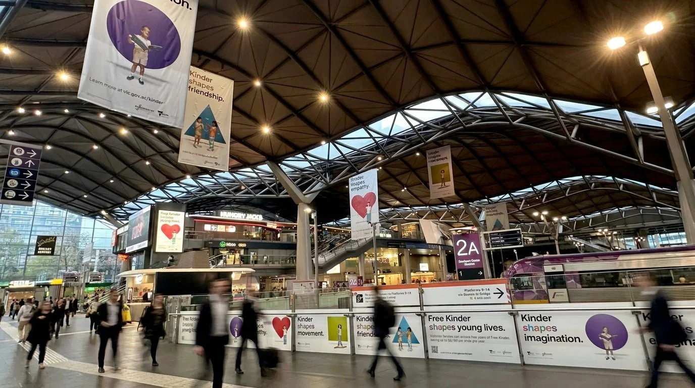 Free Kinder banners in a train station concourse, including 'Kinder shapes friendship.' and 'Kinder shapes imagination.'