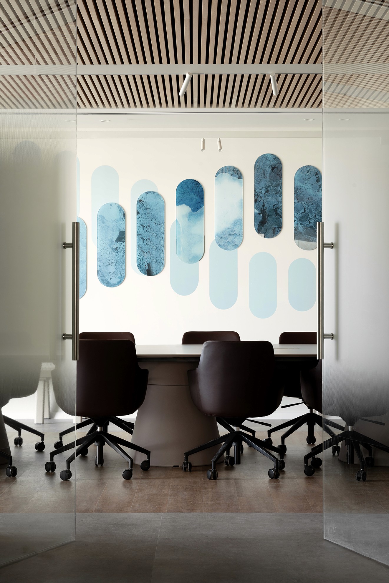 חדר ישיבות ייצוגי: חלל פגישות מרווח עם שולחן מנהלים, כיסאות עור כהים ואלמנטים אקוסטיים המשתלבים בעיצוב.