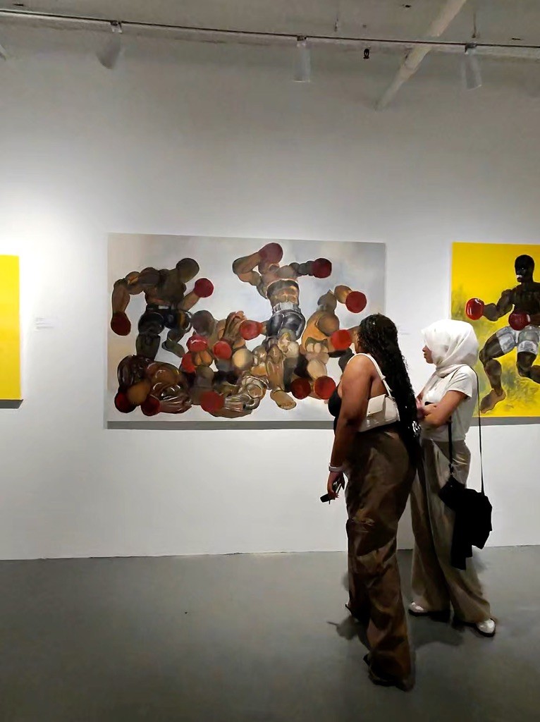 Visitors viewing paintings across the gallery wall