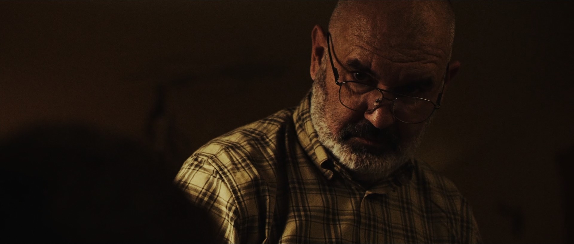Cinematic interior shot of two men drinking at a table, low-key lighting.