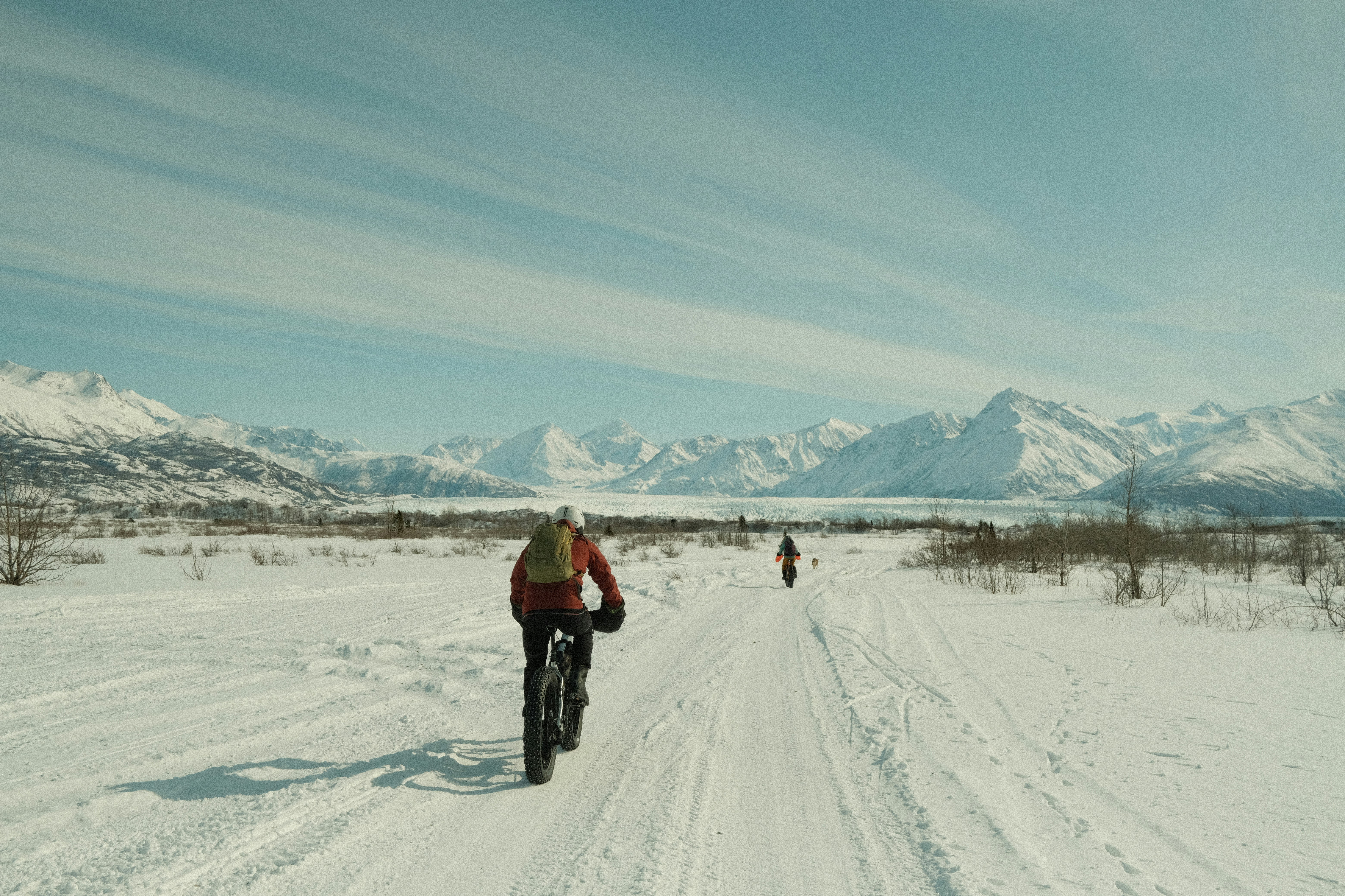 Two people riding fat-tire bikes on a snowy path.
