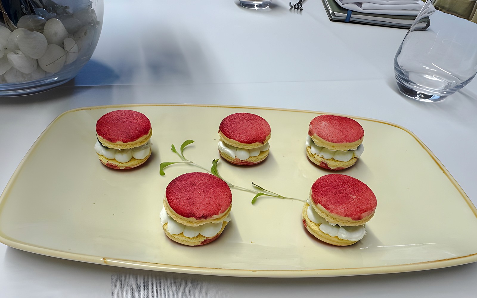 Small red macarons with white cream filling on a plate.