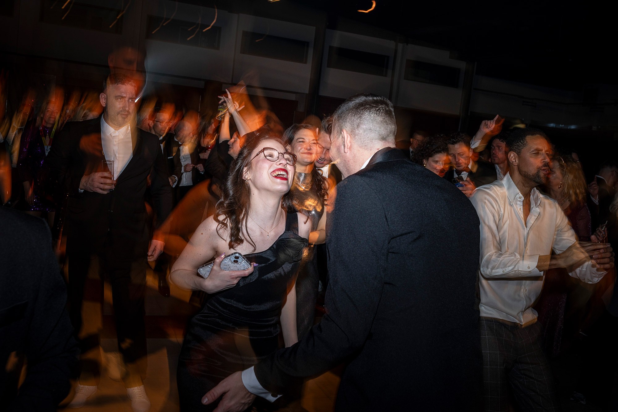 Guests dancing and celebrating at a corporate conference afterparty with dynamic motion blur and warm stage lighting.