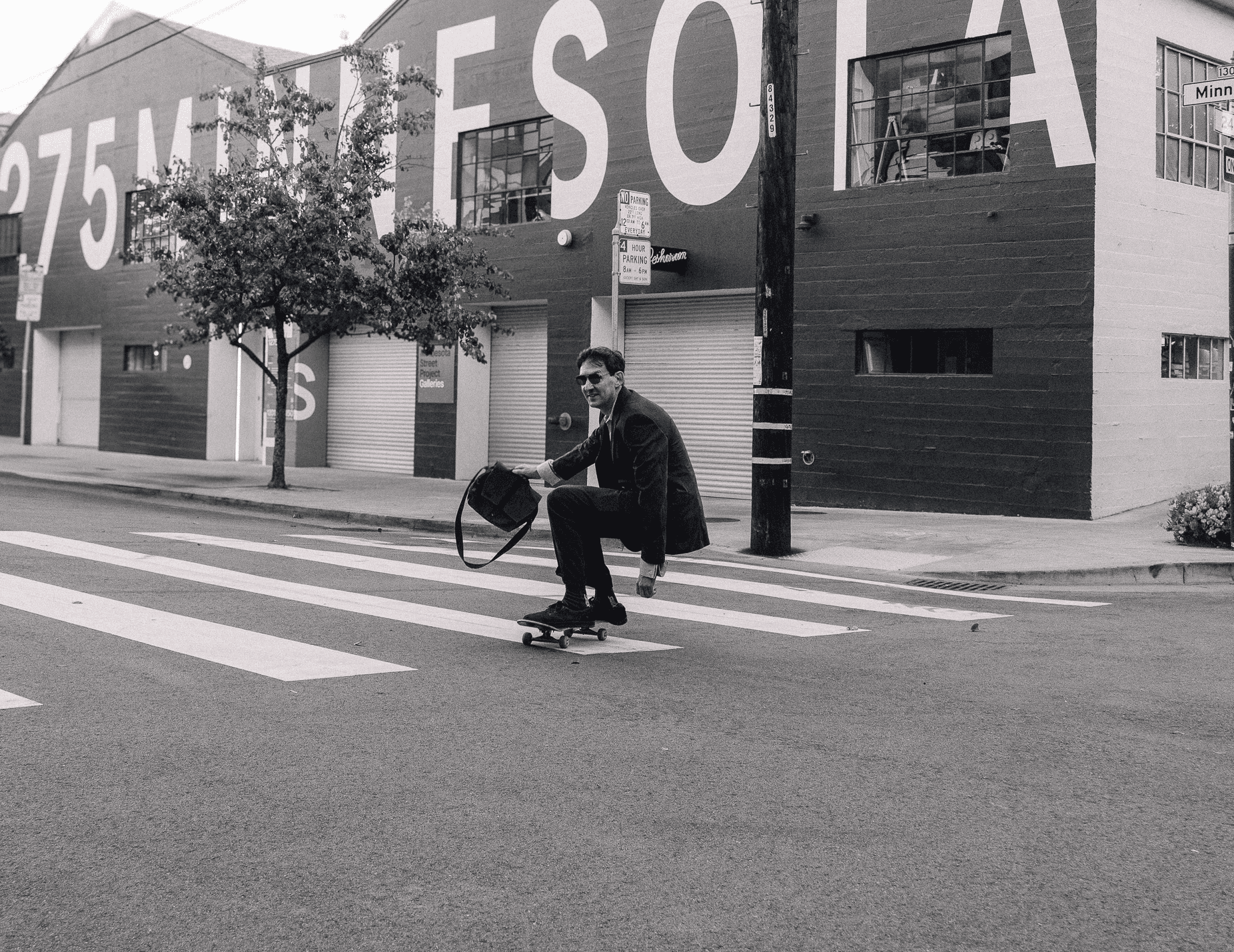 Chris Potts skateboarding in a suit while holding a briefcase