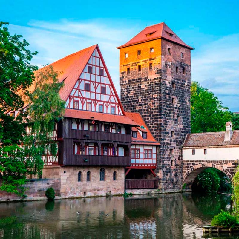 New York City skyline at twilight featuring the Empire State Building and other skyscrapers illuminated against a purple-blue sky.
