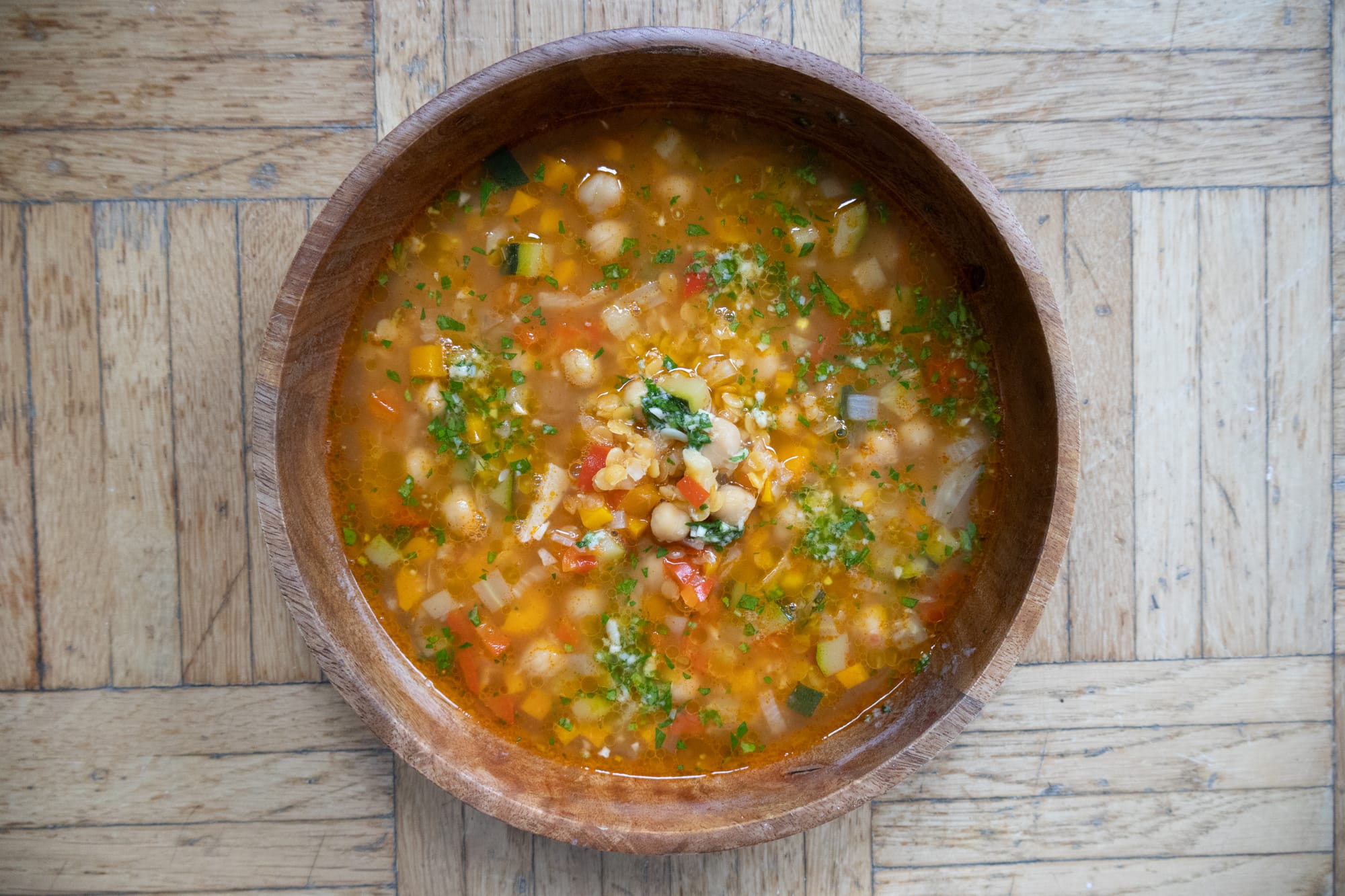 Zu sehen ist eine Schüssel aus Vogelperspektive. Der Inhalt der Schüssel ist eine tomatig-bunte Minestrone Suppe.