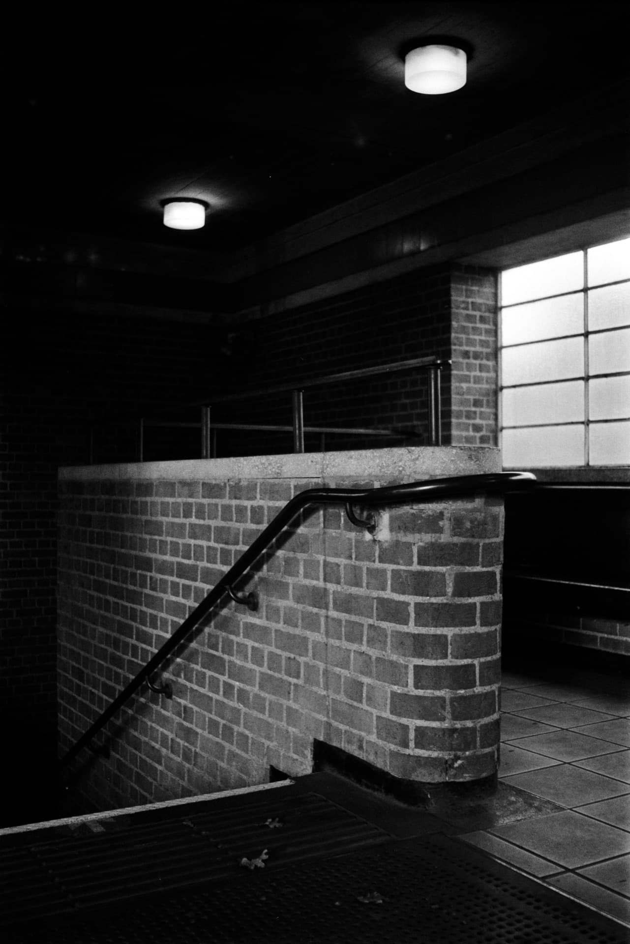 Brick stairwell with handrail and illuminated window at underground station